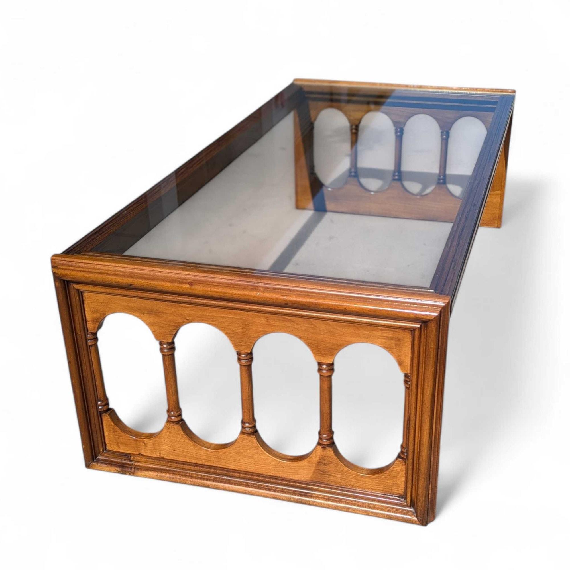 Une élégante table à cocktail du milieu du siècle, fabriquée dans une riche finition noyer, avec des côtés en fuseau arqué sophistiqués et une surface en verre fumé.

Influences du design - Mid-Century Modern, Hollywood Regency, Transitional.

Le