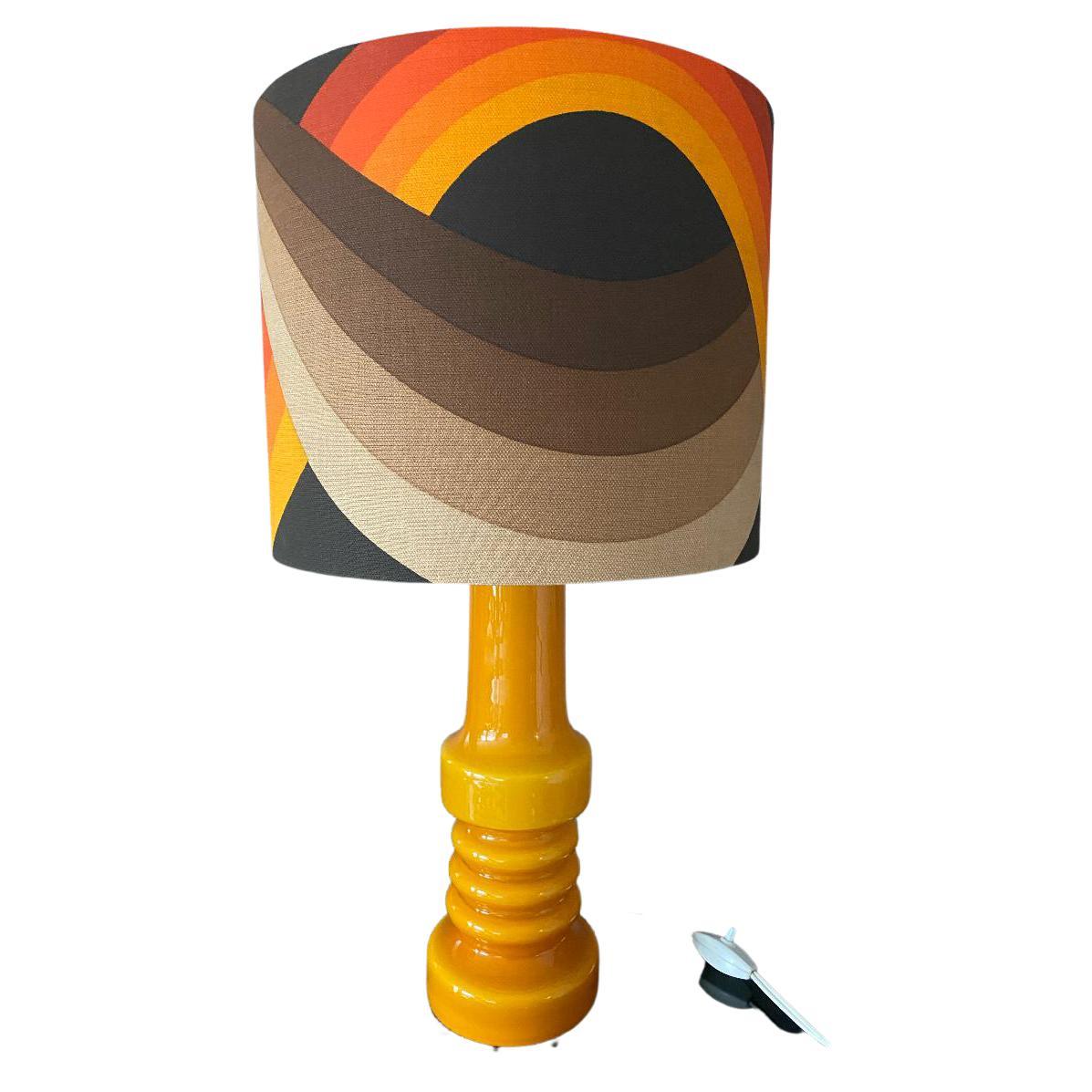 Vibrant lamp of the renown Holmegaard glass factory located in Fensmark, Denmark. The company was founded 1823.
This lamp is in a fairly good condition, and has a lampshade newly made with a 1970s fabric.

Measures: Lamp is 38cm high, including