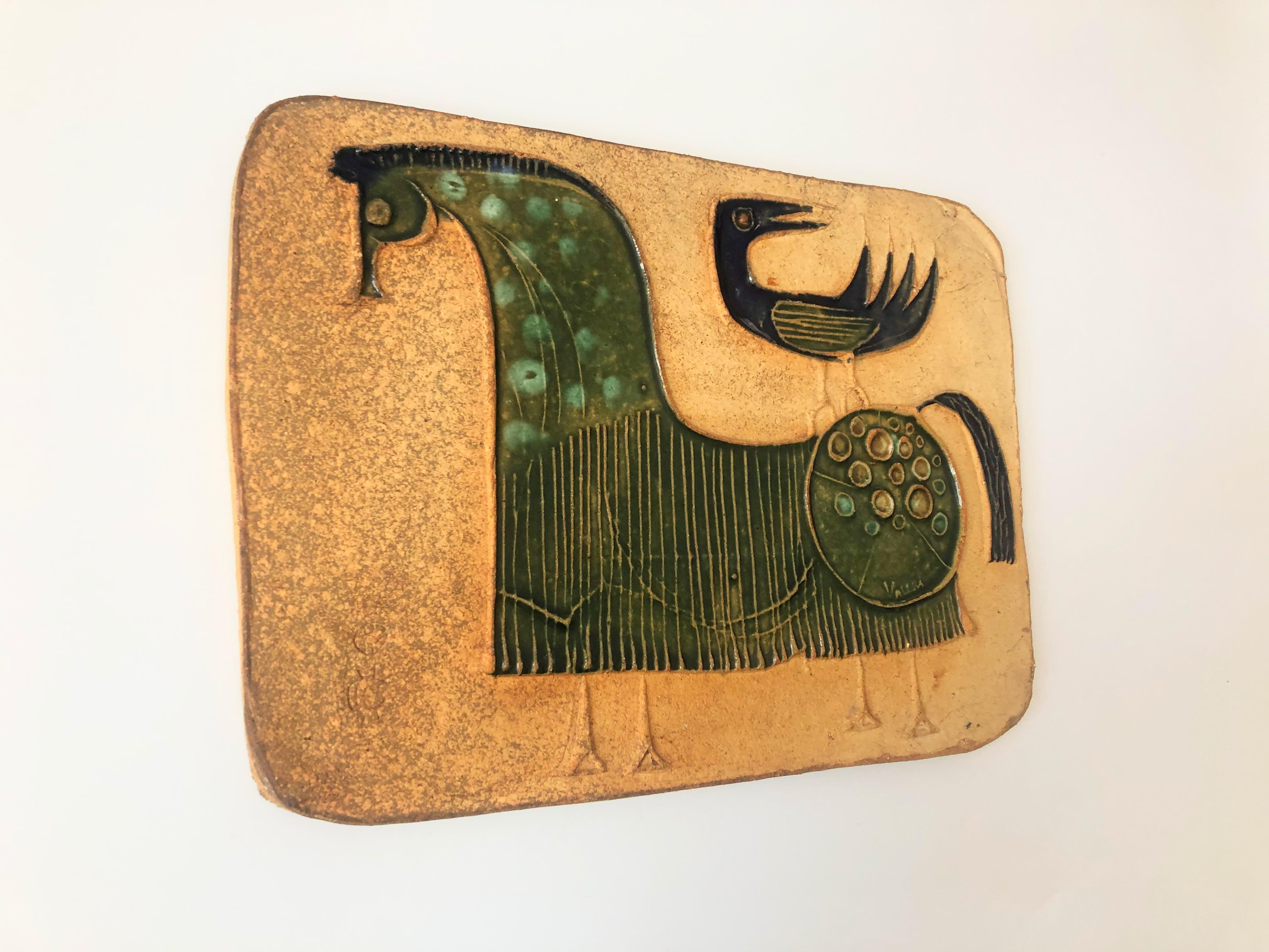 A mid century art pottery wall plaque by Bertil Vallien for the Hal Fromhold Studio. Features a beautiful stylized image of a horse and a bird in glossy dark green and blue glazes contrasting nicely with the unglazed natural clay background.