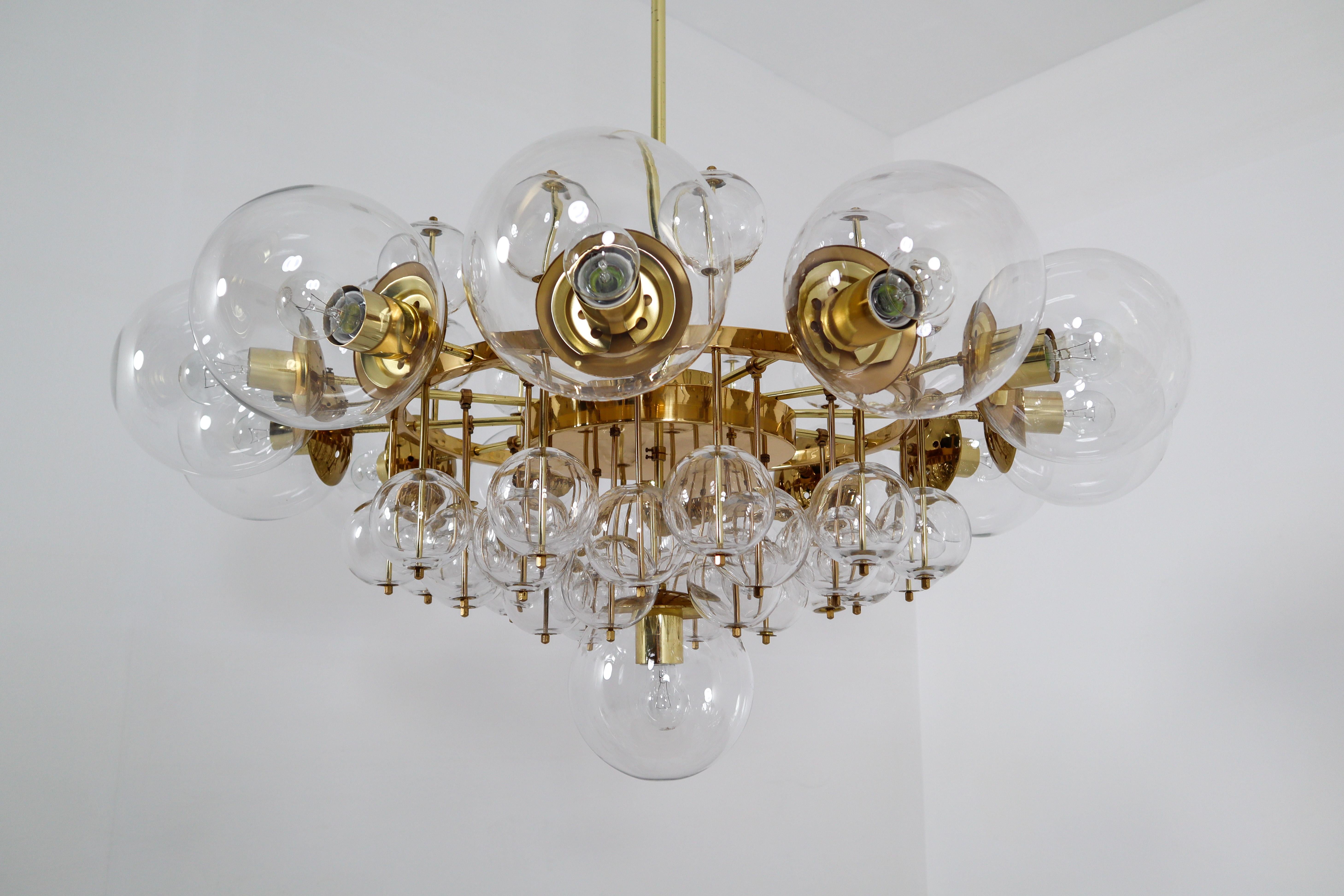 Large midcentury hotel chandelier with brass fixture, large hand blowed glass globes and smaller hand blowedglass globes. The pleasant light it spreads is very atmospheric. Completed with the clear glass and brass details, this large chandelier will