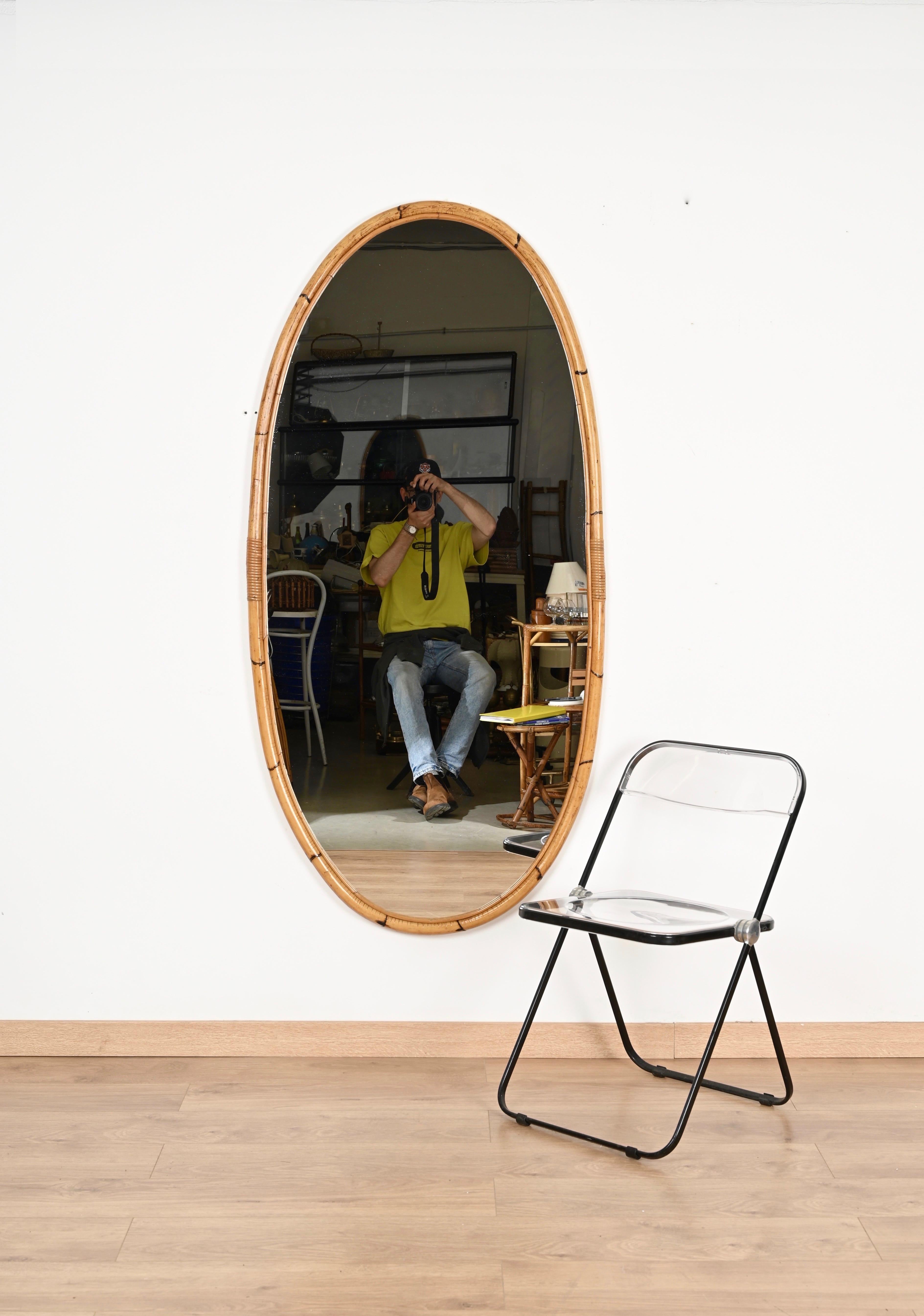 Magnifique miroir ovale de style Côte d'Azur du milieu du siècle, entièrement réalisé en bambou courbé, en rotin et en osier tressé. Cet immense miroir, incroyablement unique, a été fabriqué à la main en Italie dans les années 1960.  

Dans des