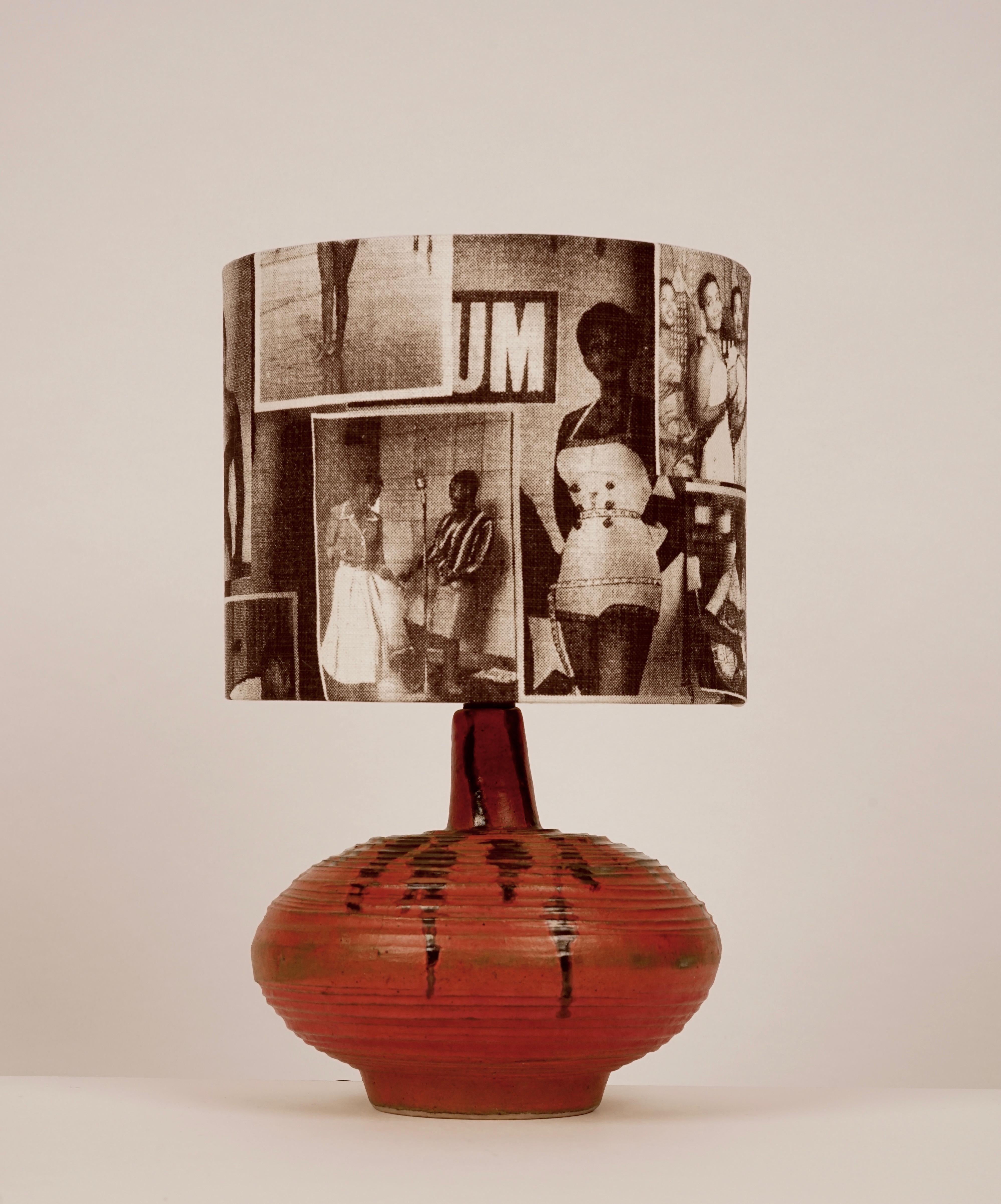 The lamp base comes from the Hungarian studio ceramic era, 1950s. The hand formed ceramic is glassed orange with dark accents. 
The lampshade has been covered in a cotton fabric with motifs from the Drum magazine.
