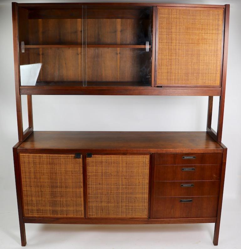 Stylish architectural hutch credenza of solid walnut with grass matte door fronts. The top cabinet has sliding glass doors, which open to shelved storage, and display, flanked by a grass matte covered door, opens to reveal more storage. The bottom