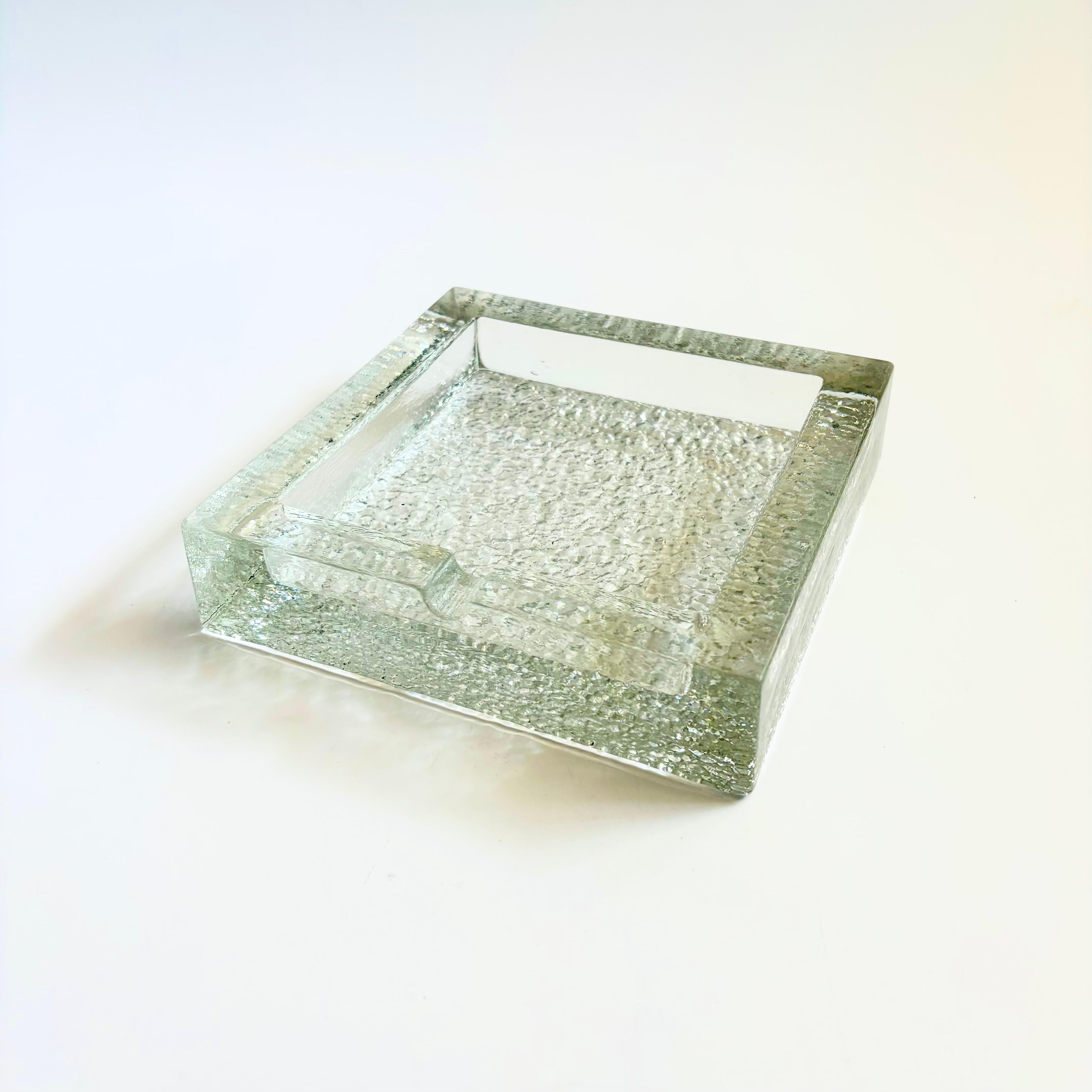 Un meraviglioso posacenere in vetro scandinavo della metà del secolo. Grande design minimalista che ricorda un blocco di ghiaccio. Forma quadrata con una singola fessura su un lato. Si tratta di un pezzo pesante con un interno liscio e un fondo