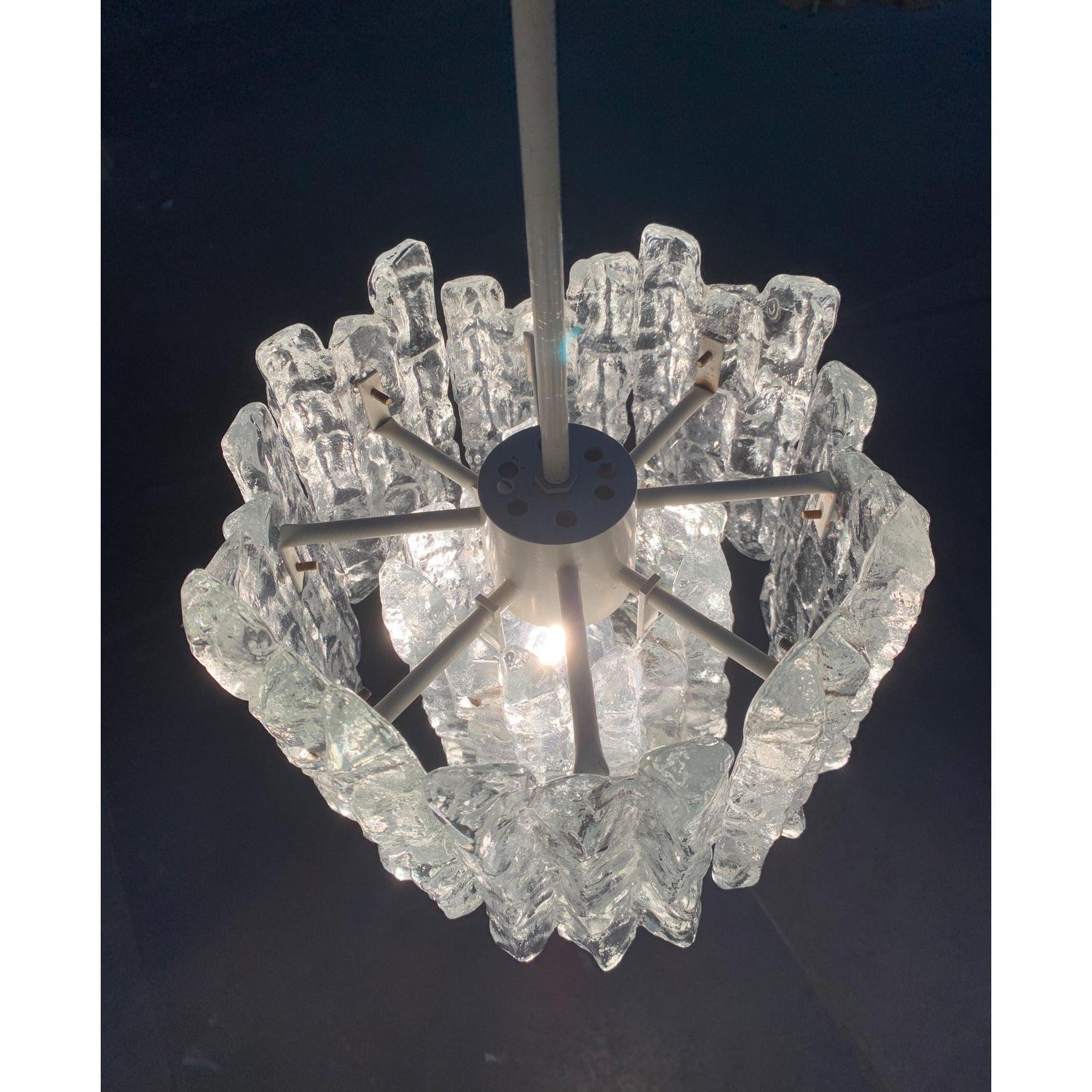 Raro candeliere in vetro di ghiaccio di Kalmar.

Imponente lampadario di Kalmar con elementi in vetro annidati. Da una parte centrale della presa, i nastri metallici di diversa lunghezza e altezza si estendono radialmente verso l'esterno.