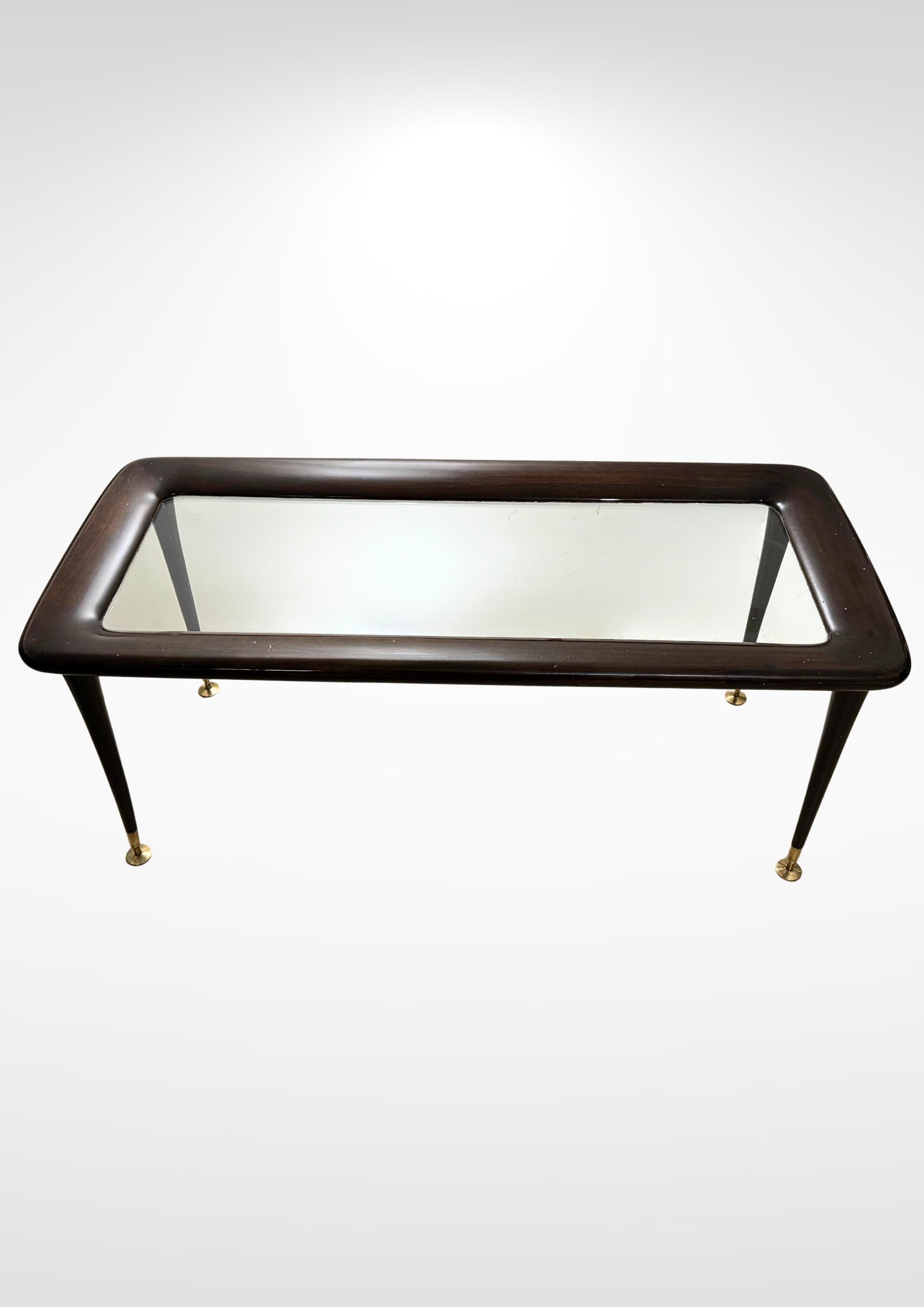 Table basse de design italien du milieu du siècle par Eco Parisi pour De Beggis, vers les années 1950.
Fabriqué en bois laqué avec un plateau en verre transparent épais, le tout supporté par 4 pieds coniques effilés avec des embouts en laiton.
Les
