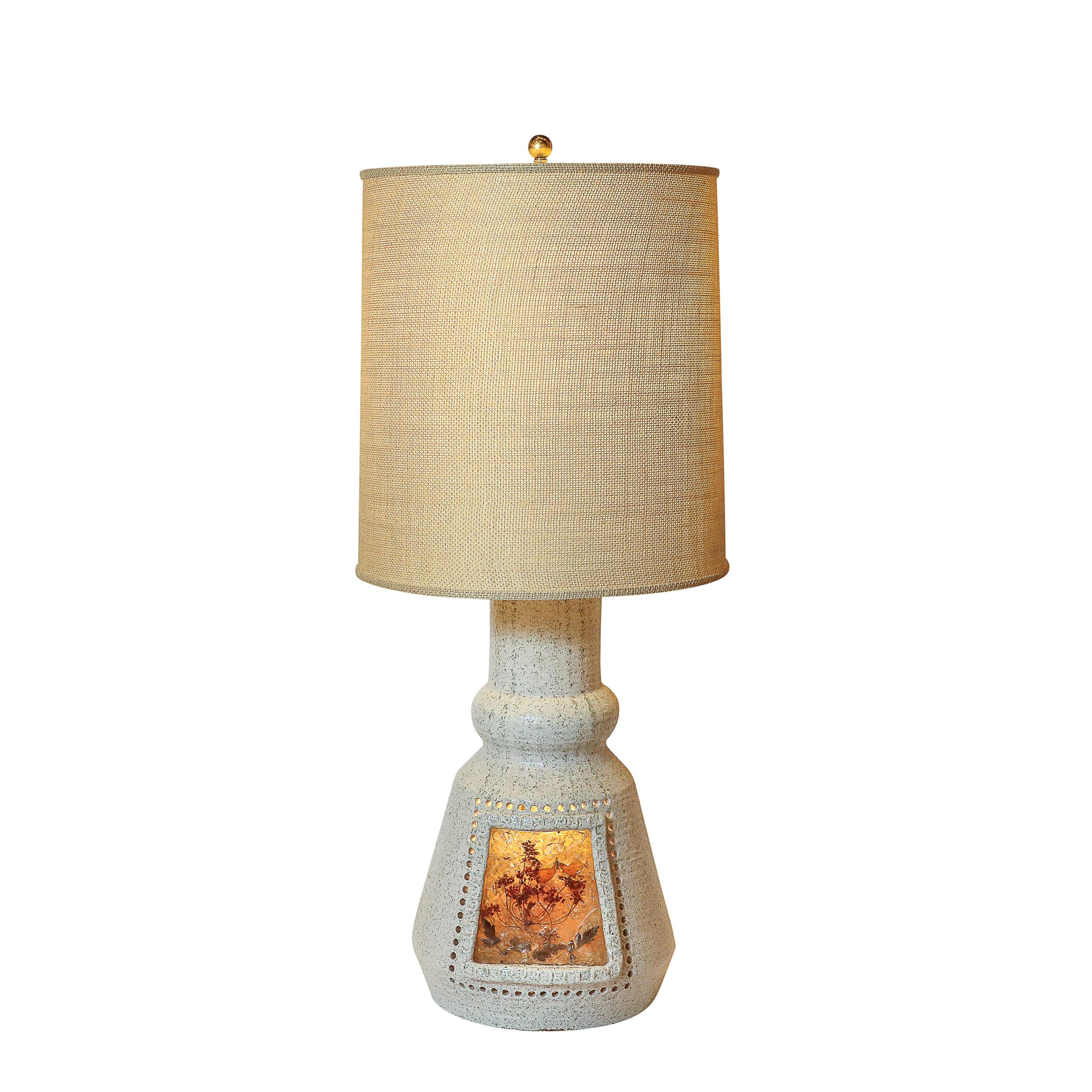 This beautifully formed and materially exquisite Mid-Century Modernist White Ceramic Table Lamp with Illuminated Amber Resin Naturalistic Motif is crafted in France, Circa 1960. This distinctive lamp is a perfect blend of mid-century design and