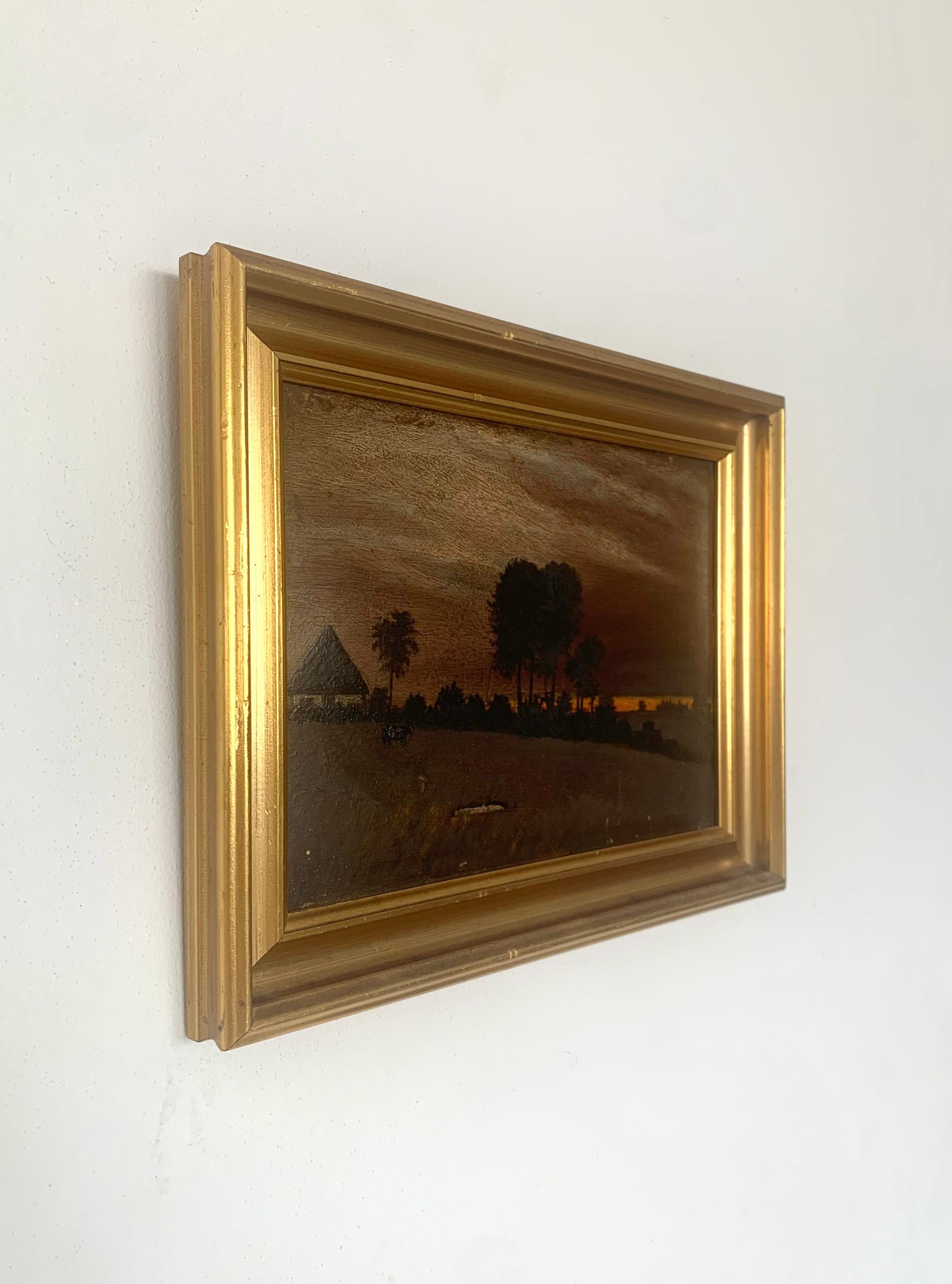 Pequeña pintura original vintage al óleo sobre tabla de un dramático atardecer o cielo crepuscular mantenido en tonos rojos y morados con una fuerte línea naranja. Los árboles y arbustos aparecen como sombras oscuras, y se ve una pequeña casa o