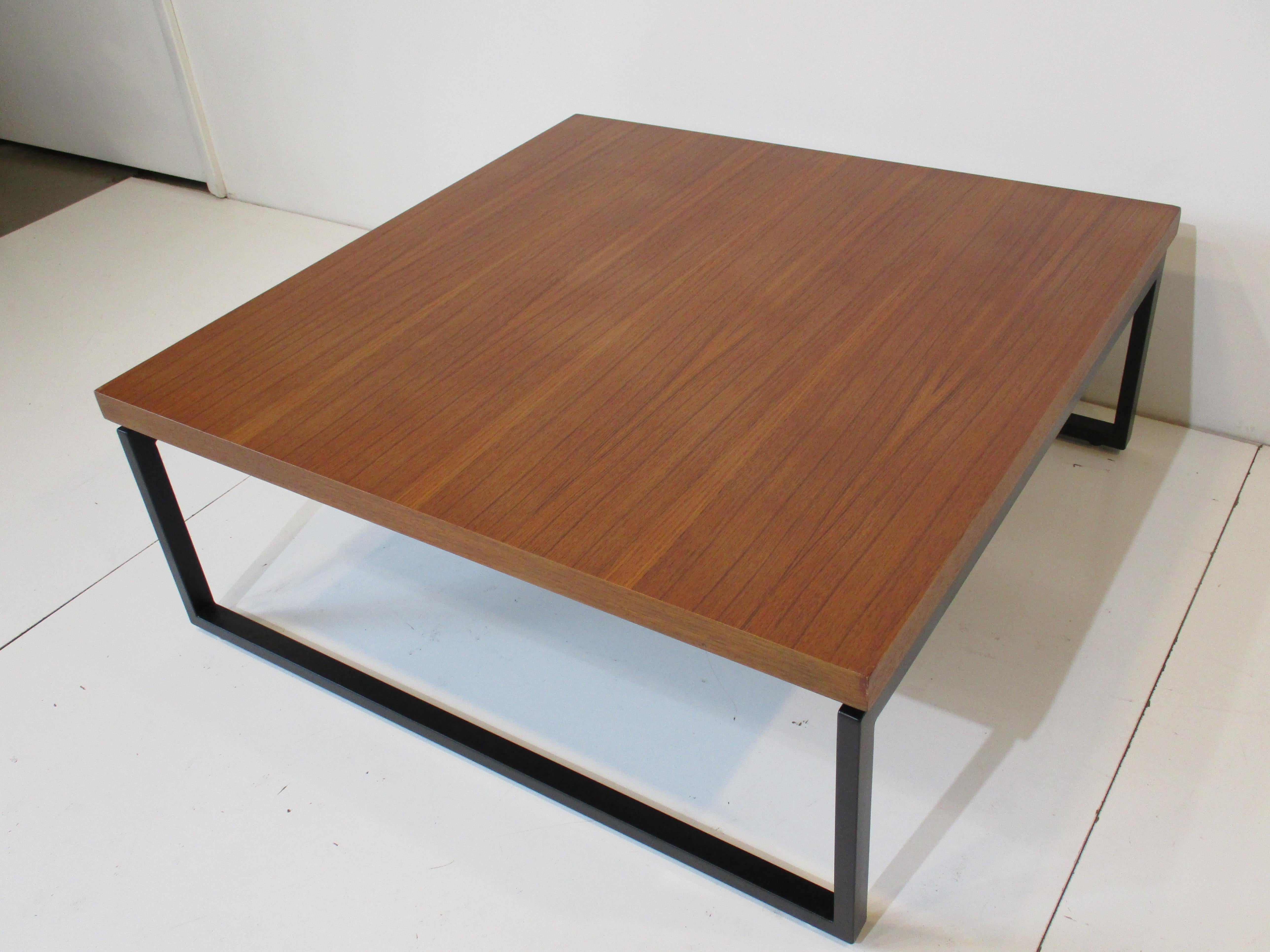 A very well grained Mid Century coffee table in a medium tone Indonesian mahogany with nickeled spacers to the legs making the top seem to float. The metal legs and frame are in satin black so the details to the table give it a rich and