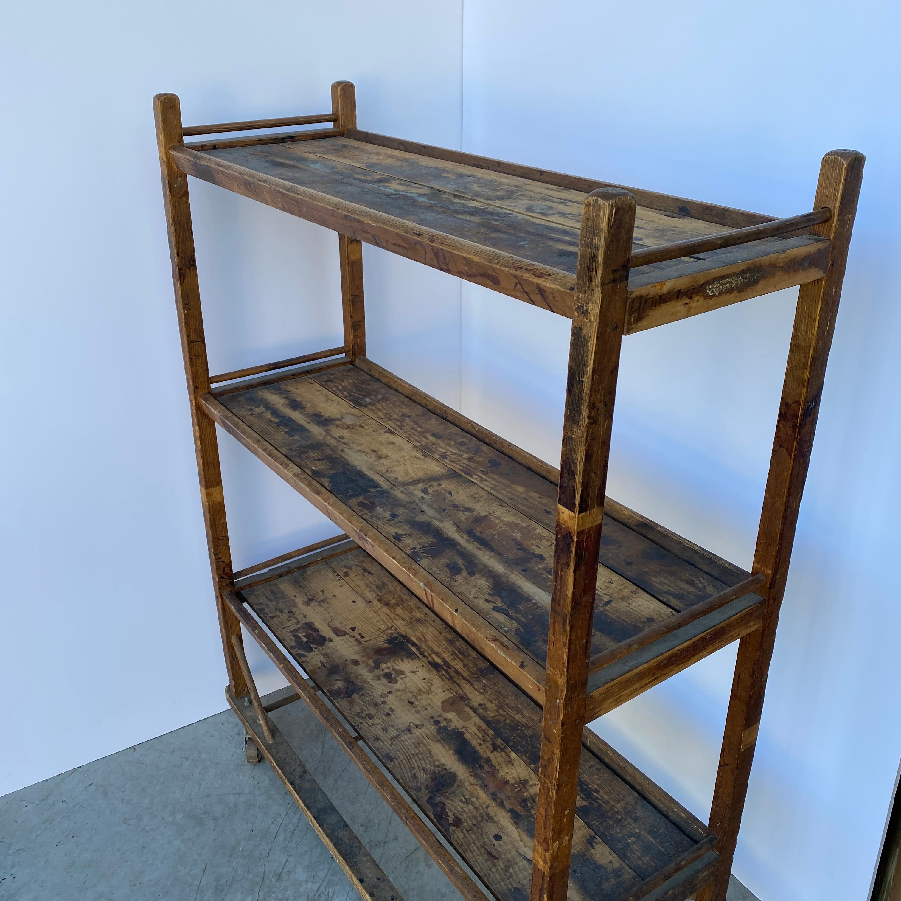 Vintage Industrial wood shelving rack. This sturdy rack on original casters has so many functions; as a shoe rack, book case or in an kitchen or pantry, will be an excellent addition to your home. All original, with vintage patina, the rack boasts 3