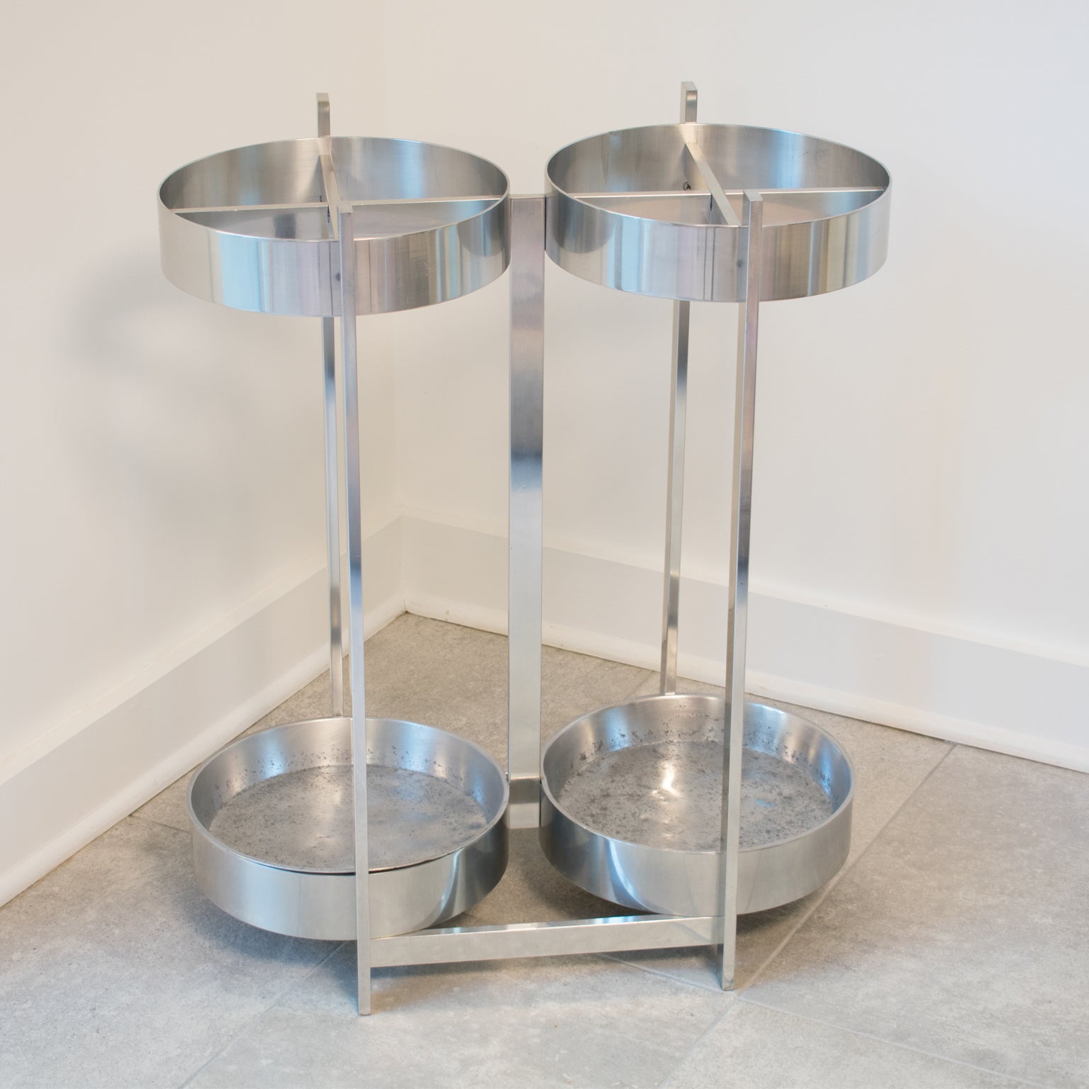 This elegant Mid-Century modernist aluminum umbrella stand or holder features an industrial Machine Age design with a large double round shape and removable inserts. There is no visible maker's mark.
This decorative accessory is in excellent