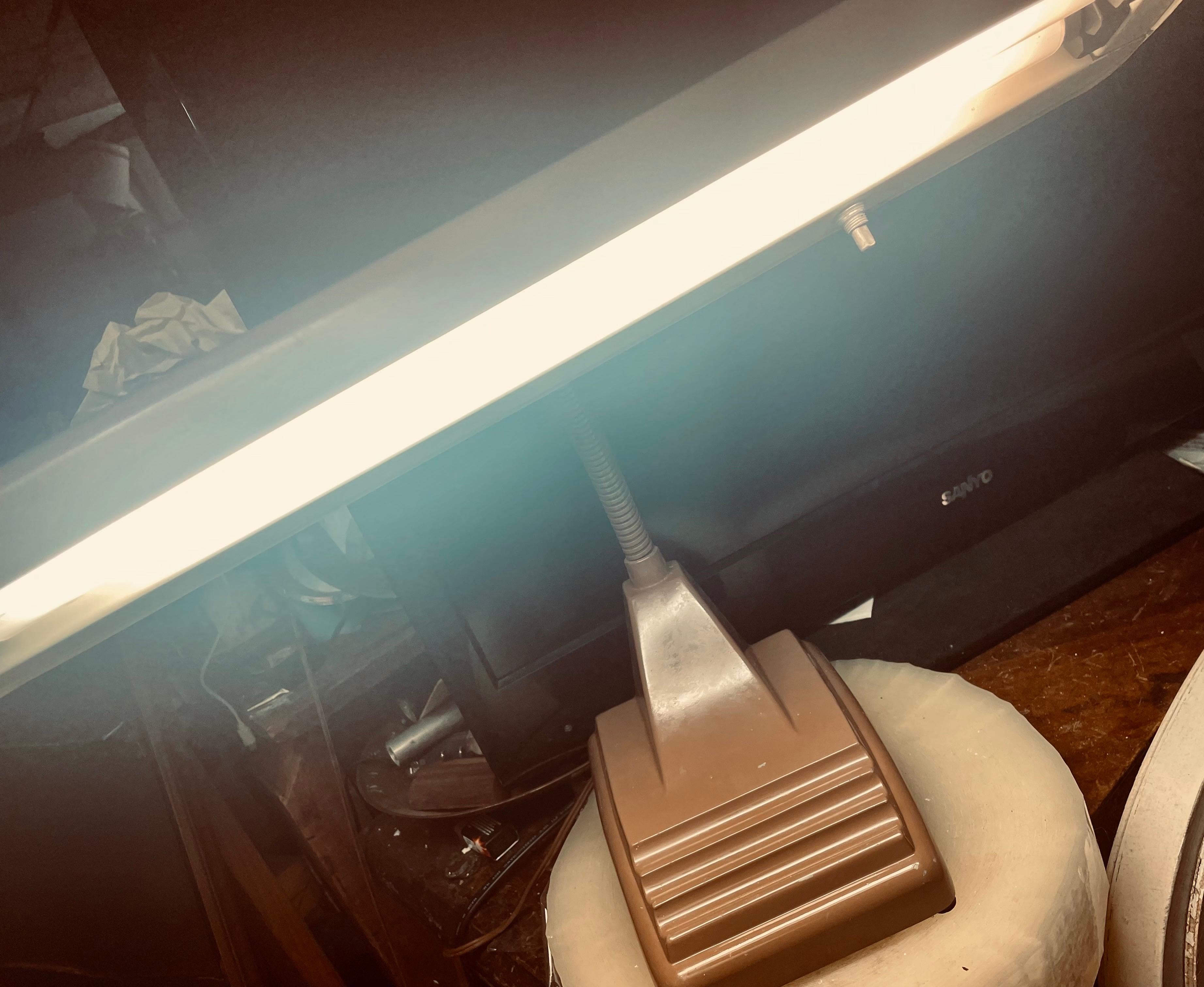 This industrial lamp has a simple art deco style and gives a factory supervisor's office vibe. It is finished in enamel paint, brown with a contrasting beige on the lamp shade, which is attached with an adjustable goose neck. The base has grooves