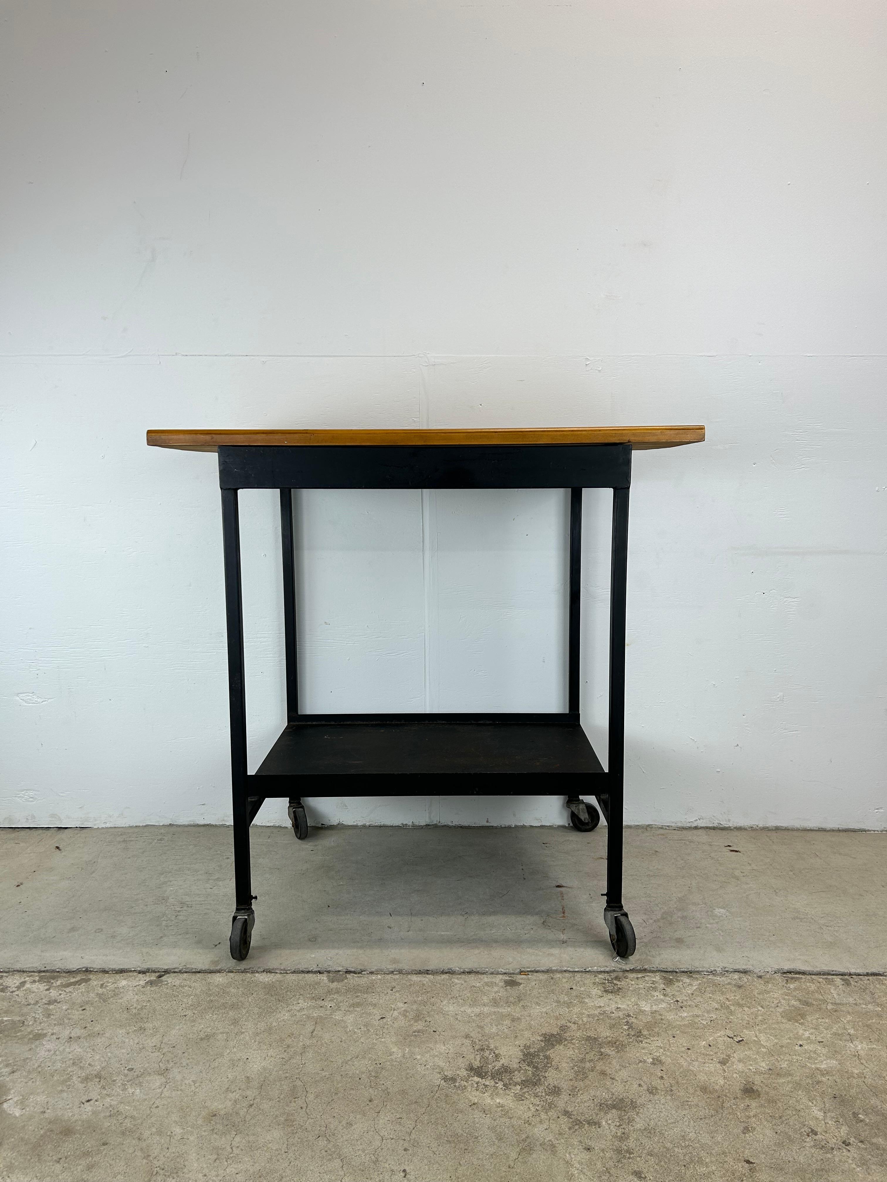 This industrial bar cart features butcher block style top, black painted metal shelf, frame and wheeled base.

Knee height: 36 inches.

Complimentary pair of industrial style bar stools available separately.

Dimensions: 40w 24d 40h 36kh

Condition: