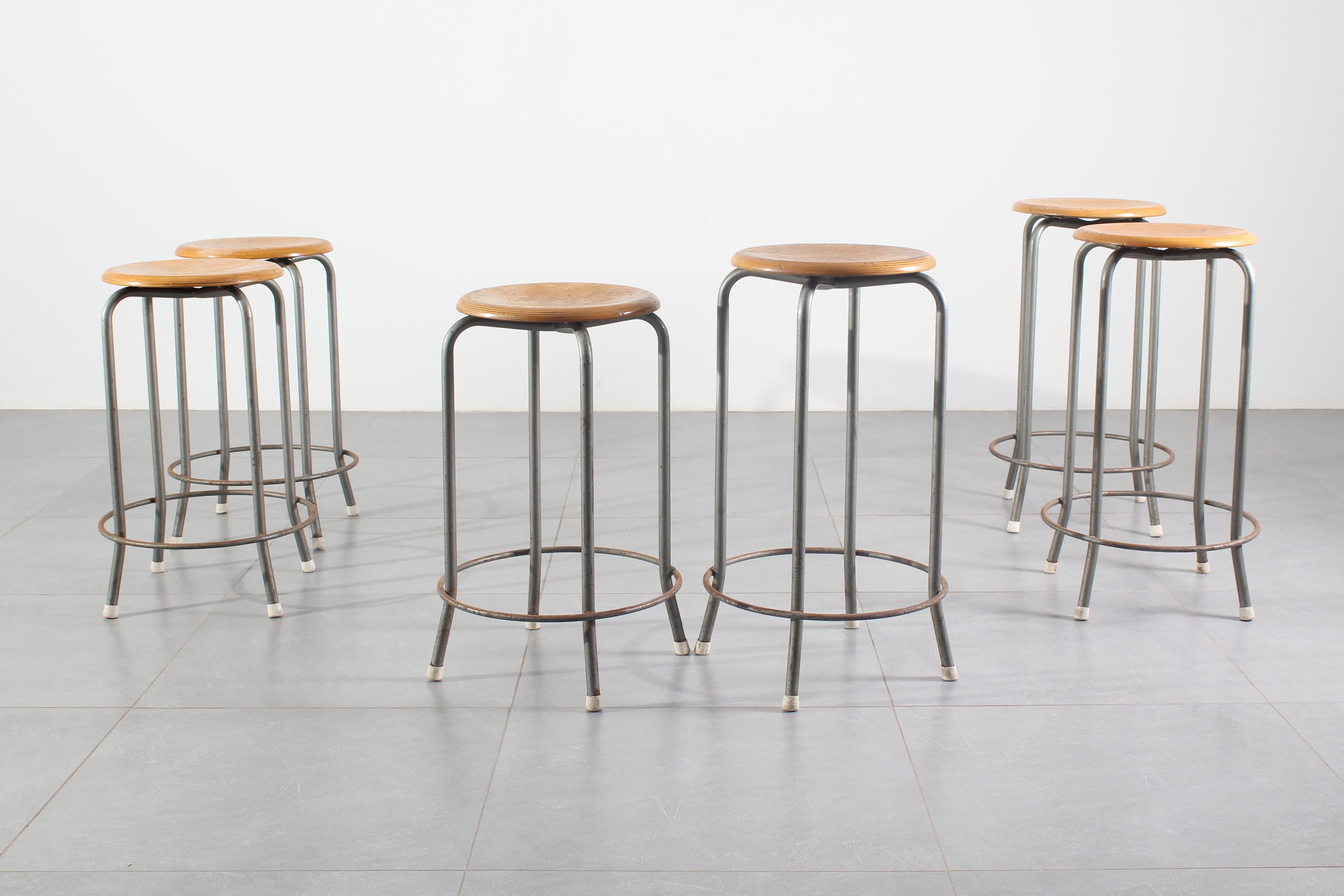 Deux séries de trois tabourets au design industriel, en deux hauteurs différentes, structure en métal avec une assise circulaire en bois. Fabriqué en Italie dans les années 1950. Usure conforme à l'âge et à l'utilisation.

Mesures (cm) :
45x45x63