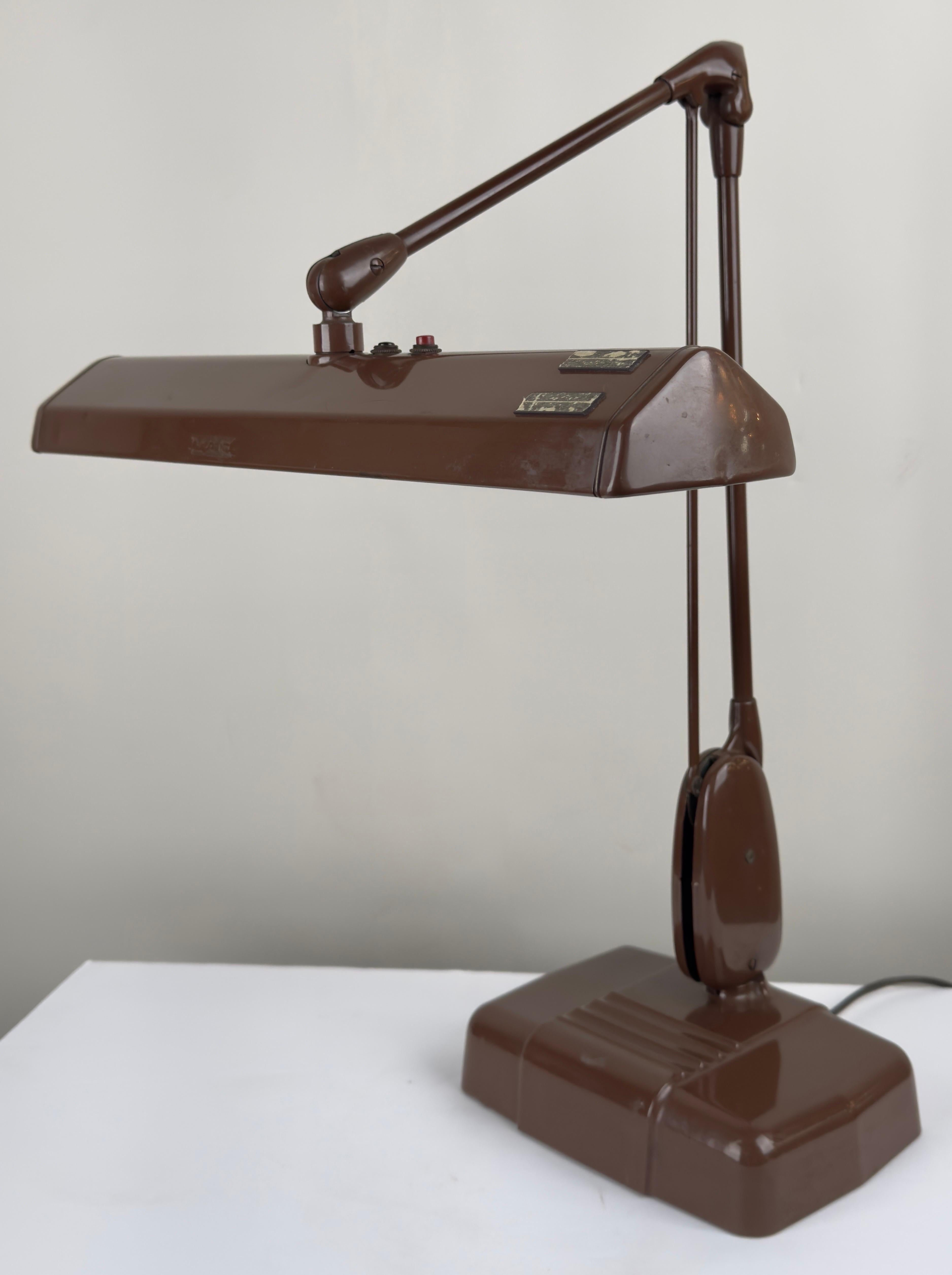 A 1950's Industrial floating fixture by Dazor model 2324, a testament to an era defined by innovation and functionality.  Crafted from robust metal and painted in a rich, lustrous brown hue, the lamp exudes an aura of rugged elegance. Its sturdy