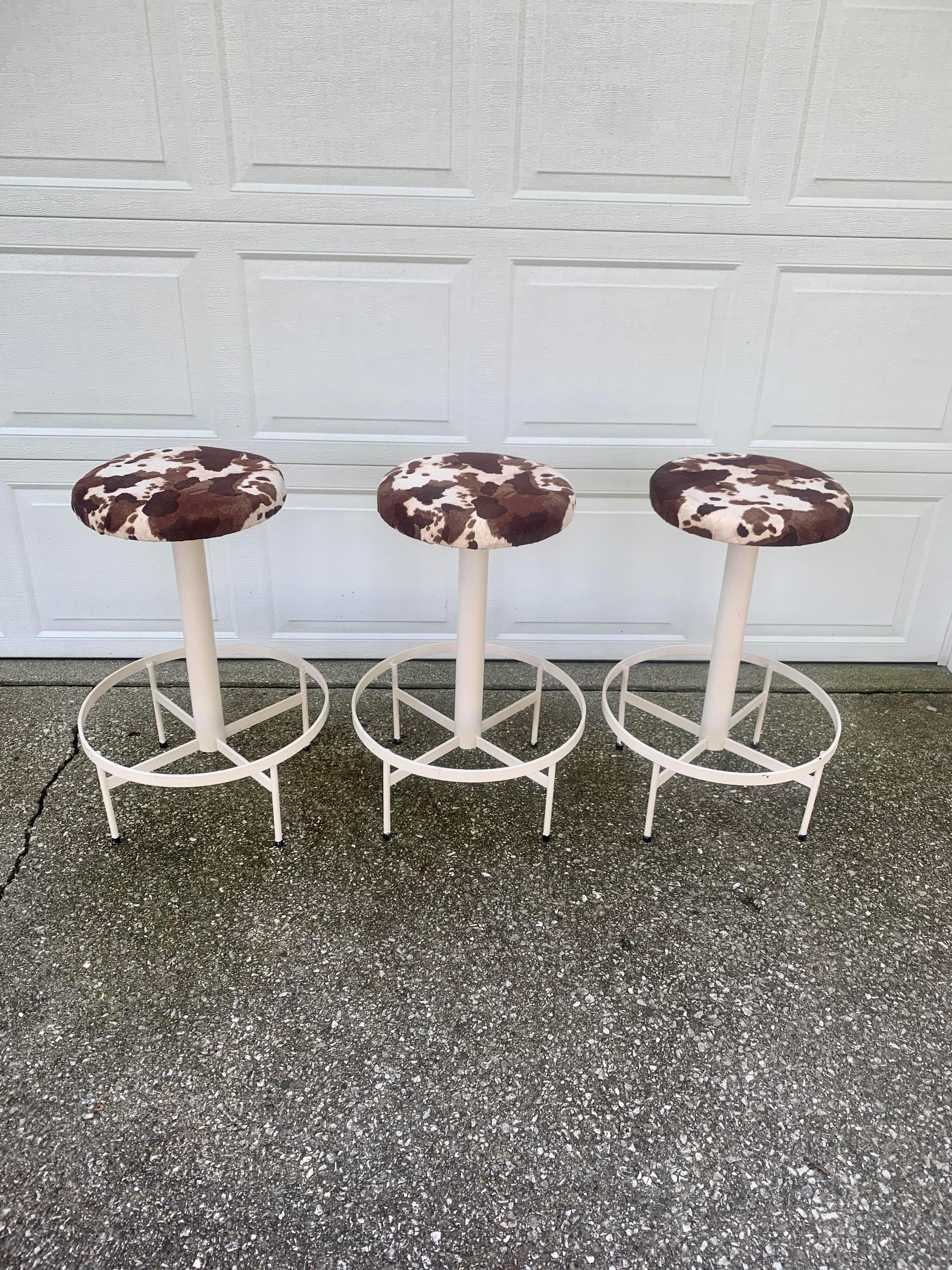 A cool set of three mid-century industrial bar stools

USA, Circa mid-20th century

Painted metal base, with cow hide patterned upholstered seats.

Measures: 19