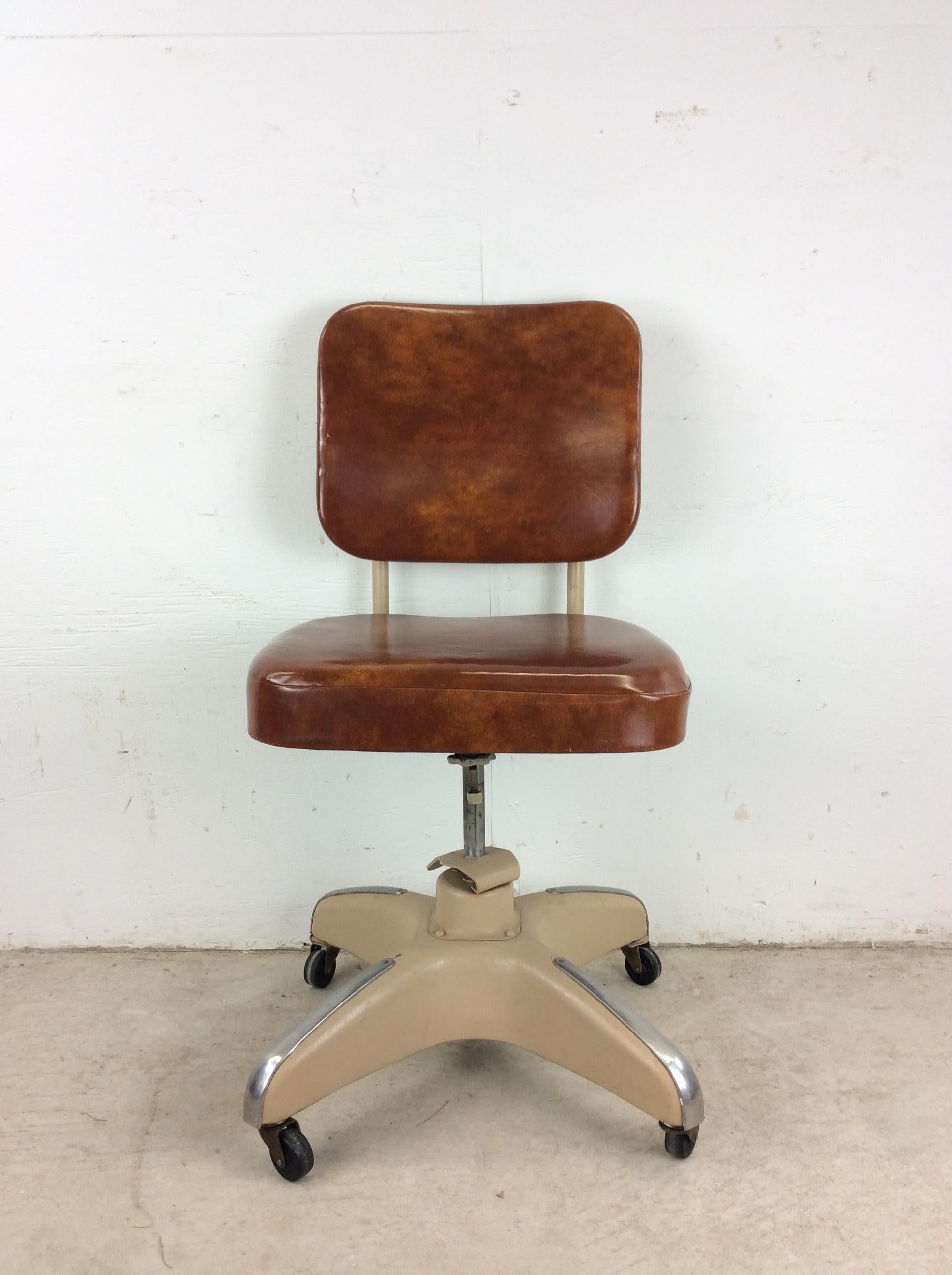 This mid century industrial office chair features steel frame, vintage brown vinyl upholstery, adjustable seat and back height, and wheeled base.

Dimensions: 18w 19.25d 35.5h 21sh 

Condition notes: Original painted finish is in good condition.