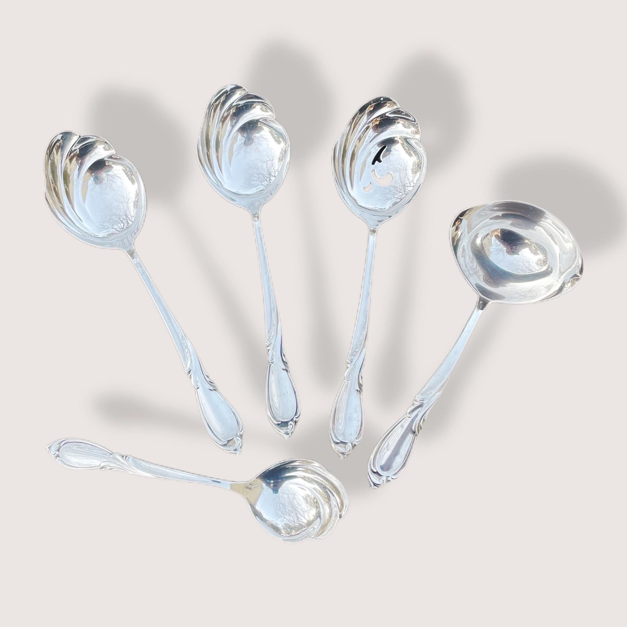 Set of five sterling serving utensils by International Silver from their Rhapsody line. They have all recently been polished. Included are two serving spoons, one pierced serving spoon, one small ladle, and a jelly spoon. All pieces are in great