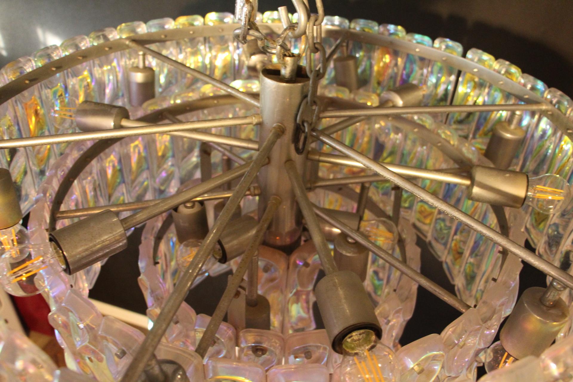 This fabulous chandelier is amazing.Indeed, its colors change according to light and surrounding.
Its Murano glass plaques change color from iridescent white to yellow,green,blue,pink and purple.
It features 4 tiers and is spectacular.
Its frame