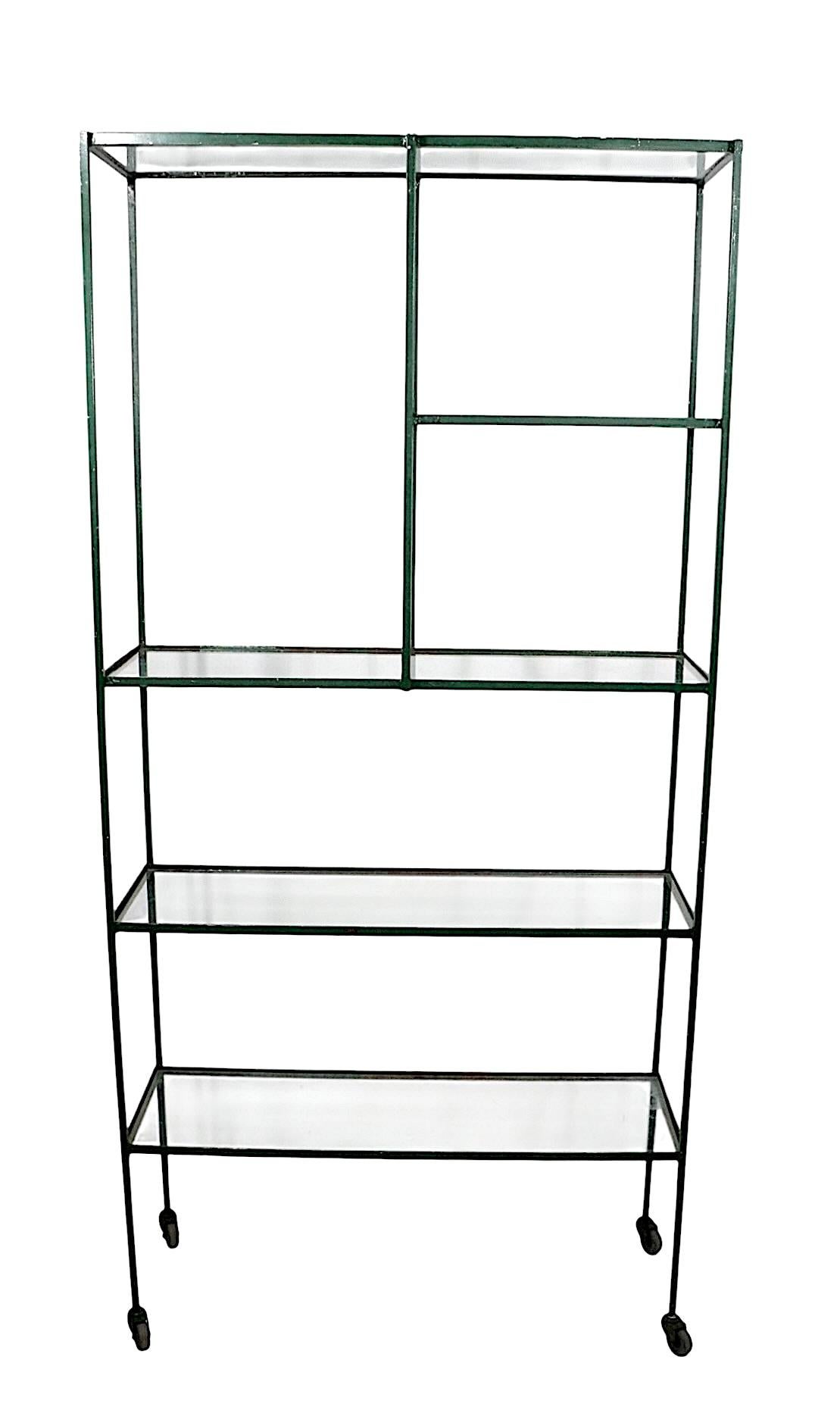Scaffale in ferro e vetro in stile industriale brutalista di metà secolo, mobile da parete, espositore. Costruito in ferro massiccio squadrato e acciaio angolare,  e vetro, con piedini originali a rotella.  Telaio saldato ben costruito con angolari