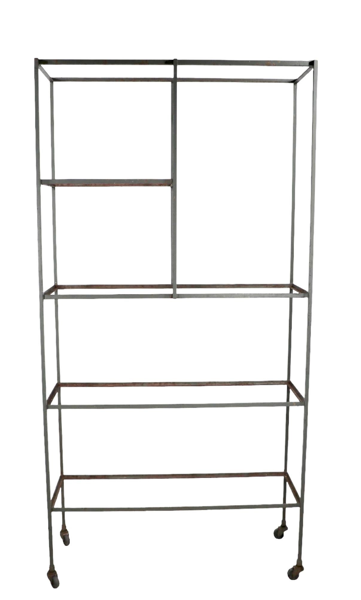 Scaffale architettonico di metà secolo in ferro e vetro, vetrina, etagere nello stile di Umanoff, Weinberg, non firmato. Questo scaffale autoportante è strutturalmente solido e robusto; presenta un'usura estetica della vernice verde chiaro e i