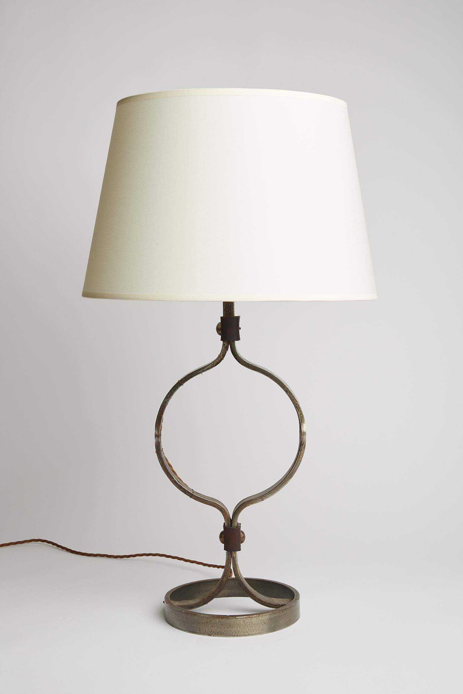 A wrought iron and studded brown leather table lamp by Jean-Pierre Ryckaert. 
France, Circa 1950
With the shade: 74 cm high by 40 cm diameter 
Lamp base only: 53 cm high by 19.5 cm diameter.