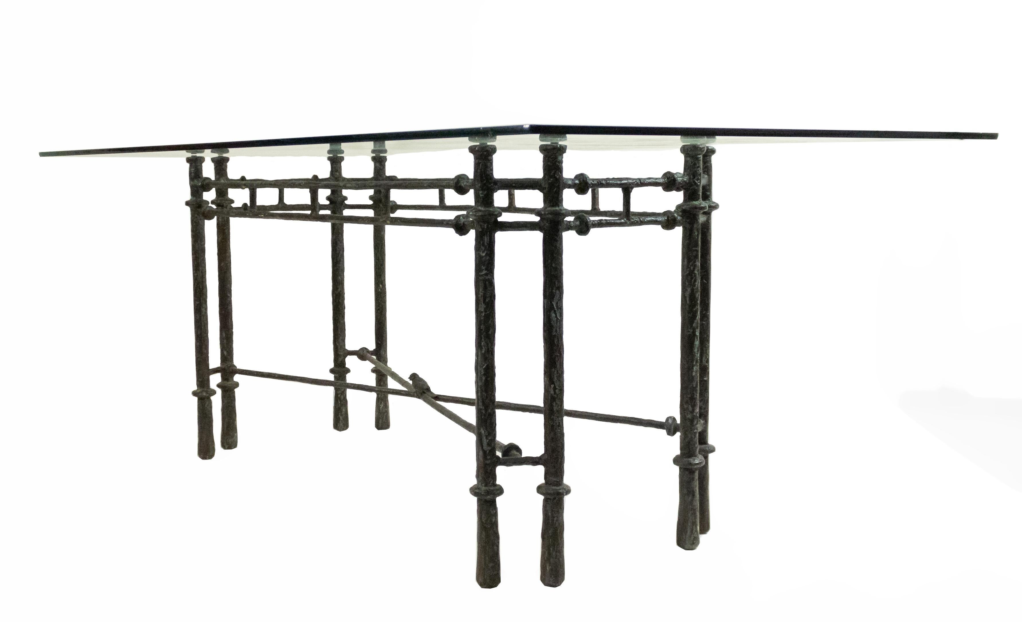 Midcentury Giacometti style dining table with a patinated dark metal base with stretcher accented with a bird supporting a rectangular glass top.