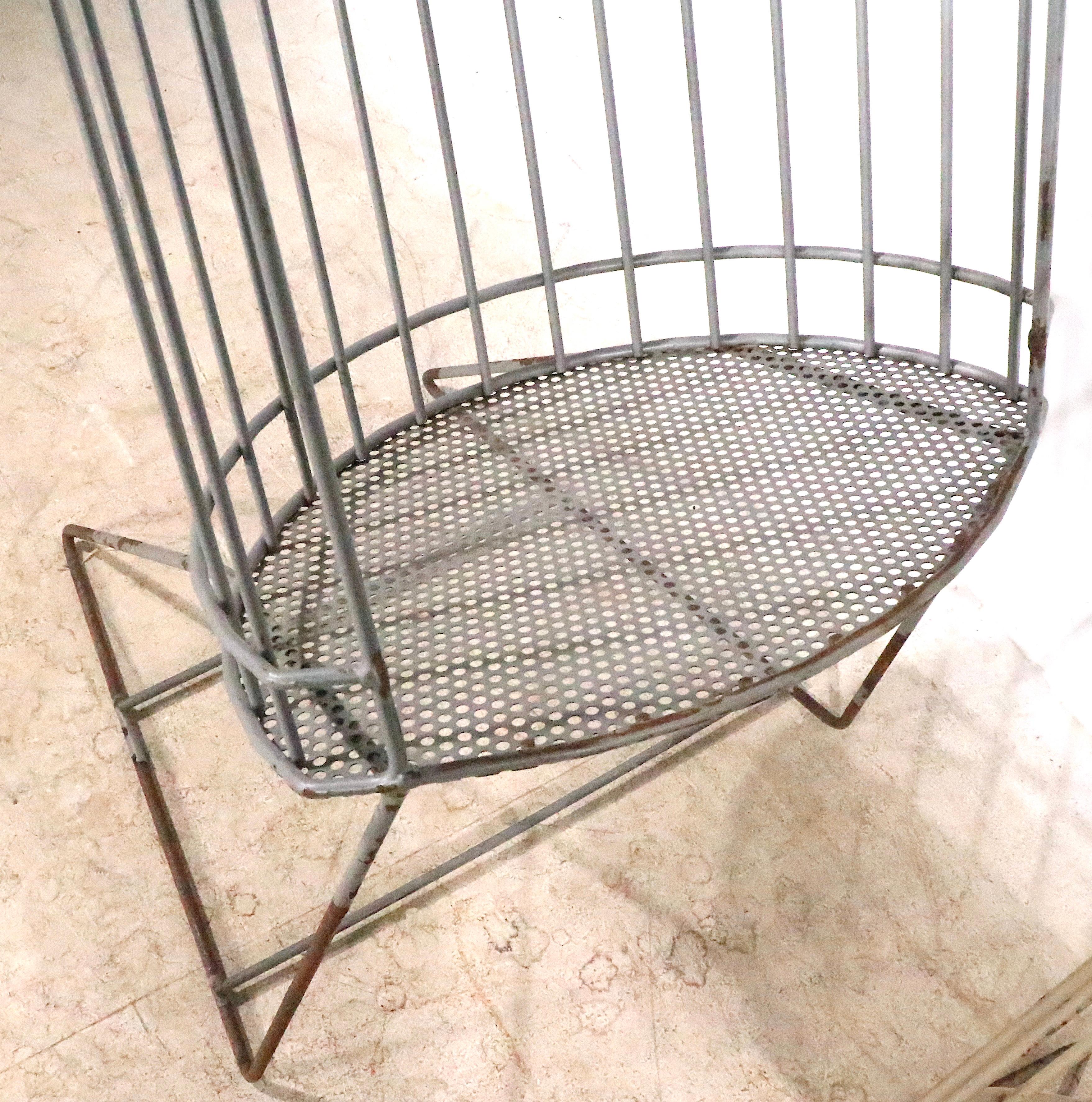 Architectural Mid Century store display stands constructed of welded iron rods, with an eye shaped bottom shelf of perforated metal.  The oval body is canted back, and has an open front to access the items within. The body rests on angled rod legs,