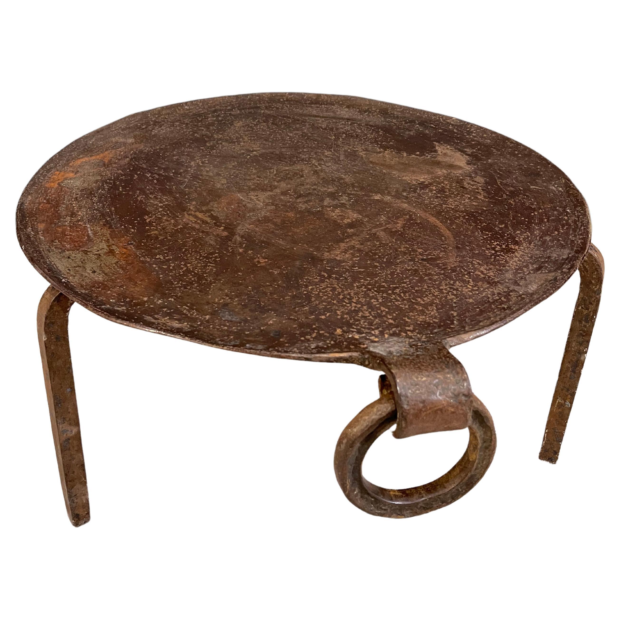 Eisentisch bestehend aus einer kreisförmigen Eisenplatte mit nach innen gebogenem Rand und einem Ring, der diesem Tisch seinen ganzen Stil verleiht. Das Tablett steht auf einem eisernen Stativfuß.
