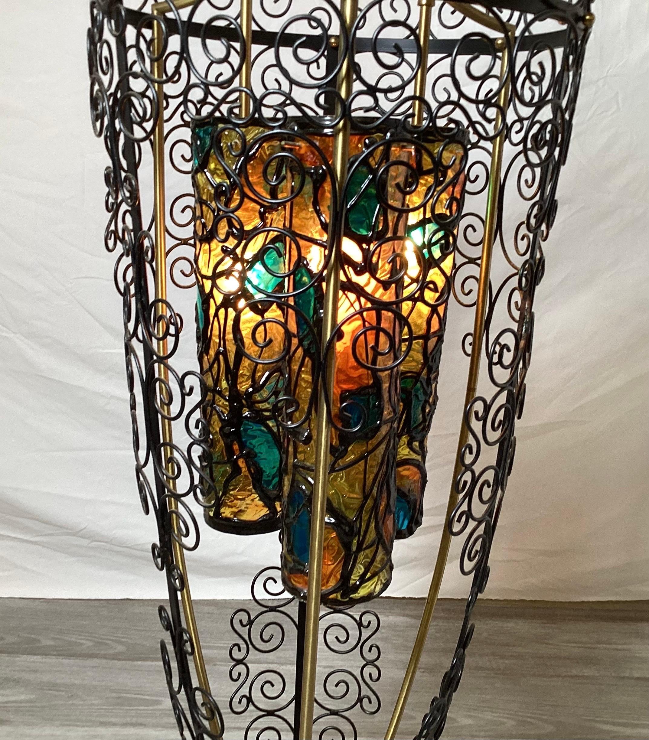 An open urn shape table lamp with three plastic stained glass shades. The iron bird gage urn form with burnished brass supports, 10 inch diameter at the bottom, 14.5 dimeter at the top, 45 inches tall. Whimsical mid century design.