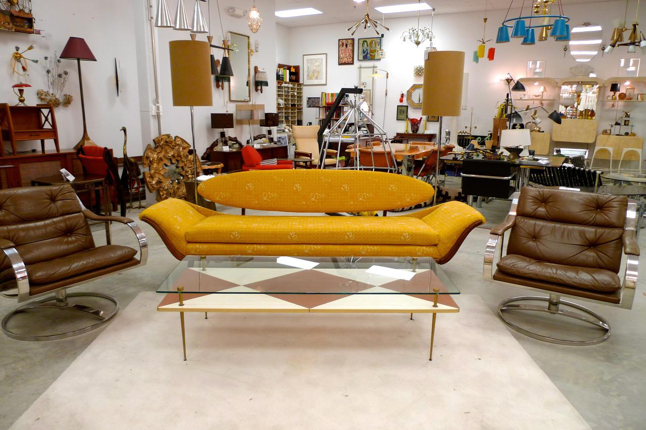 1950's two-tier rectangular glass top cocktail table floating above bold graphic ivory and brown leather diamond harlequin design supported by tapered brass stiletto legs and standoffs with mounts..
