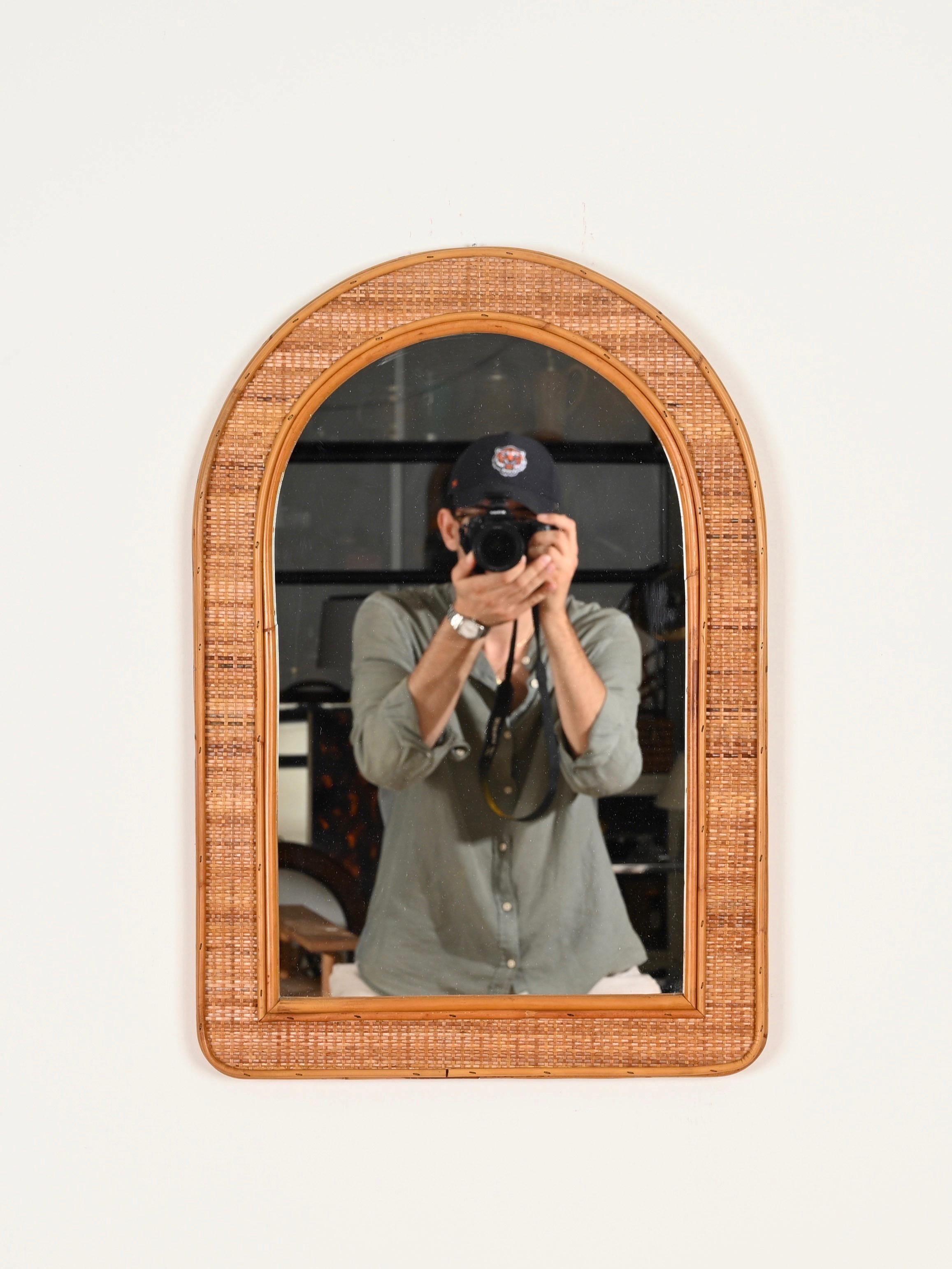 Magnifique miroir arqué en bambou et osier tressé de style Côte d'Azur. Ce charmant miroir organique a été produit en Italie dans les années 1970.

En fabuleux état et d'une charmante couleur miel. Le miroir a un triple cadre en bambou courbé qui