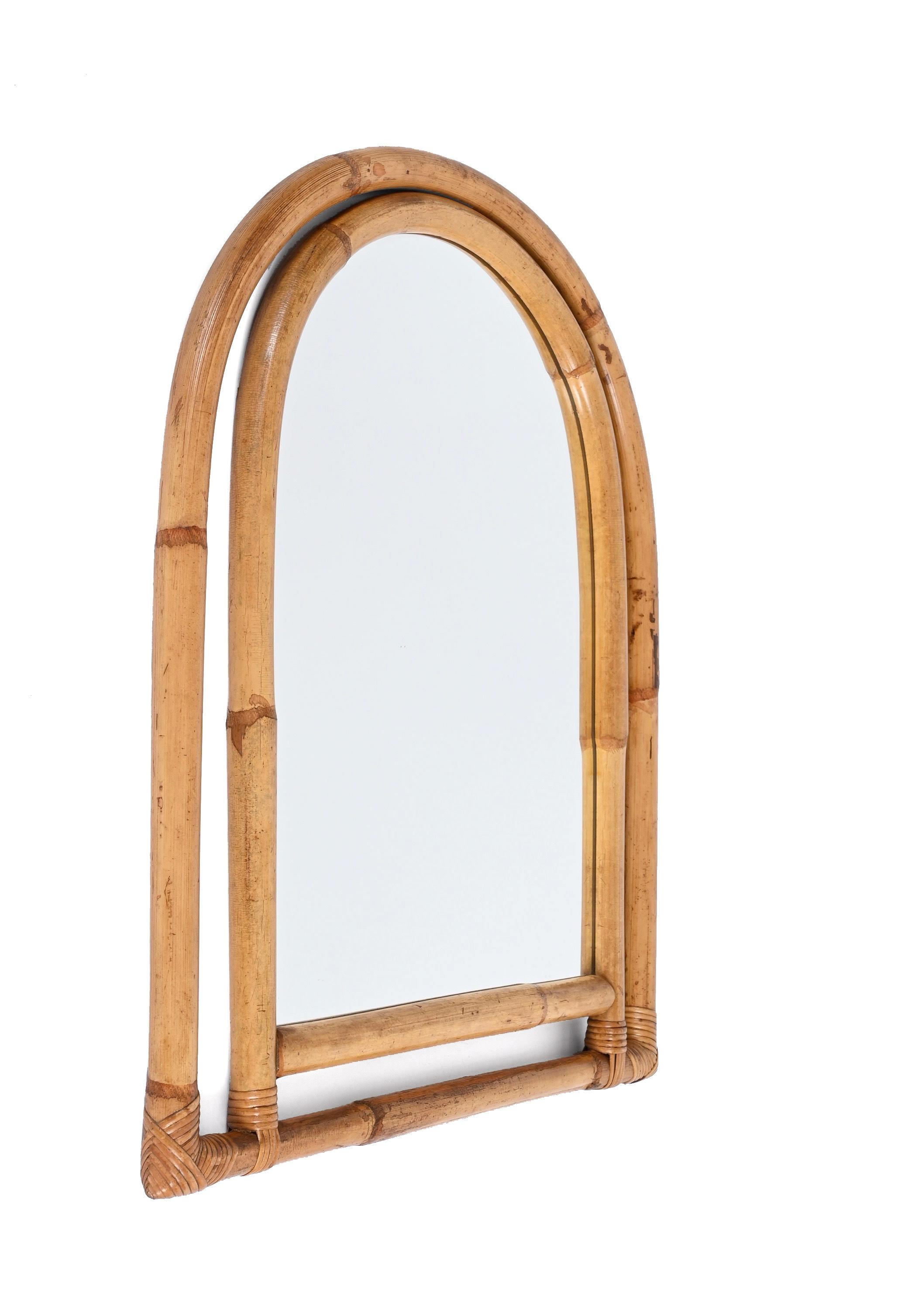 Midcentury arched mirror with a stunning double frame in curved bamboo and rattan wicker. This fantastic item was produced in Italy in the 1970s.

The way the two-round bamboo lines and the glass integrate via the sinusoidal wicker is superb and
