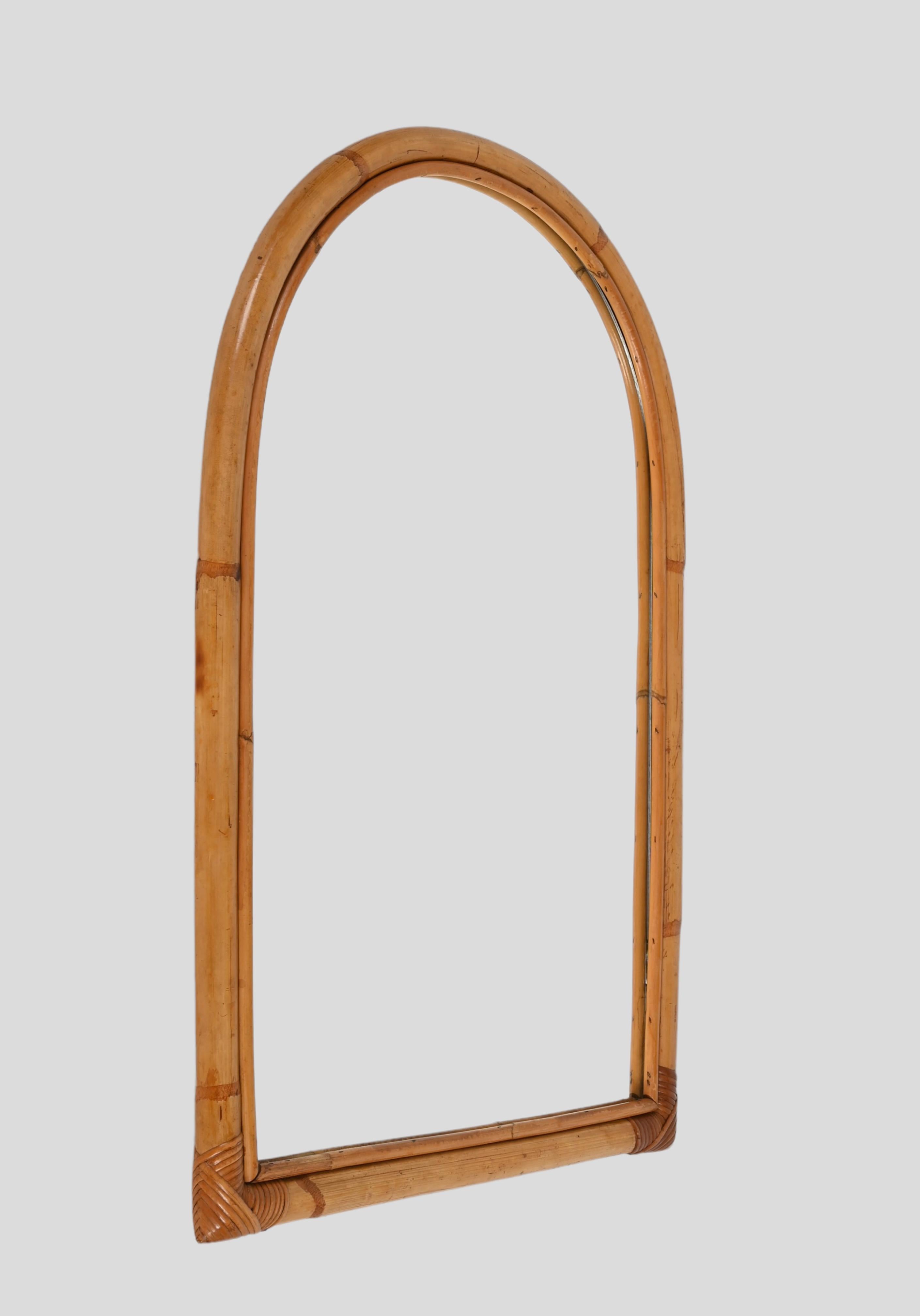 Wonderful mid-century arched shaped mirror with double bamboo cane frame. This fantastic item was produced in Italy in the 1970s.

The way the two-round bamboo lines and the glass integrate via the sinusoidal wicker is superb and conveys infinite