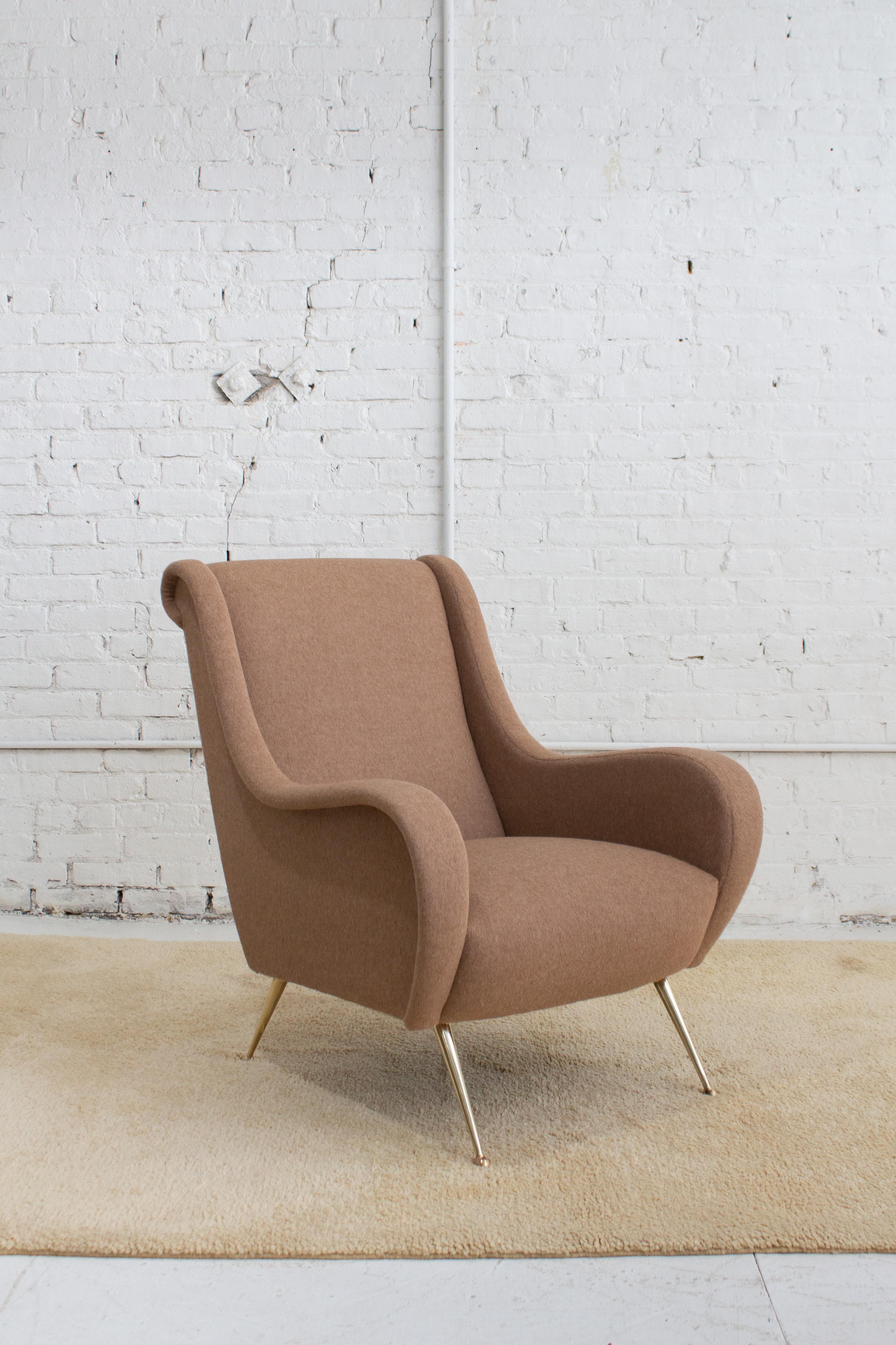 A mid century Italian armchair attributed to Giuseppe Rossi Di Albizzate. A sculptural arm wraps up to the headrest creating a stylized silhouette. Brass feet. Newly reupholstered in a soft textured beige wool. Sourced in Northern Italy. Pair