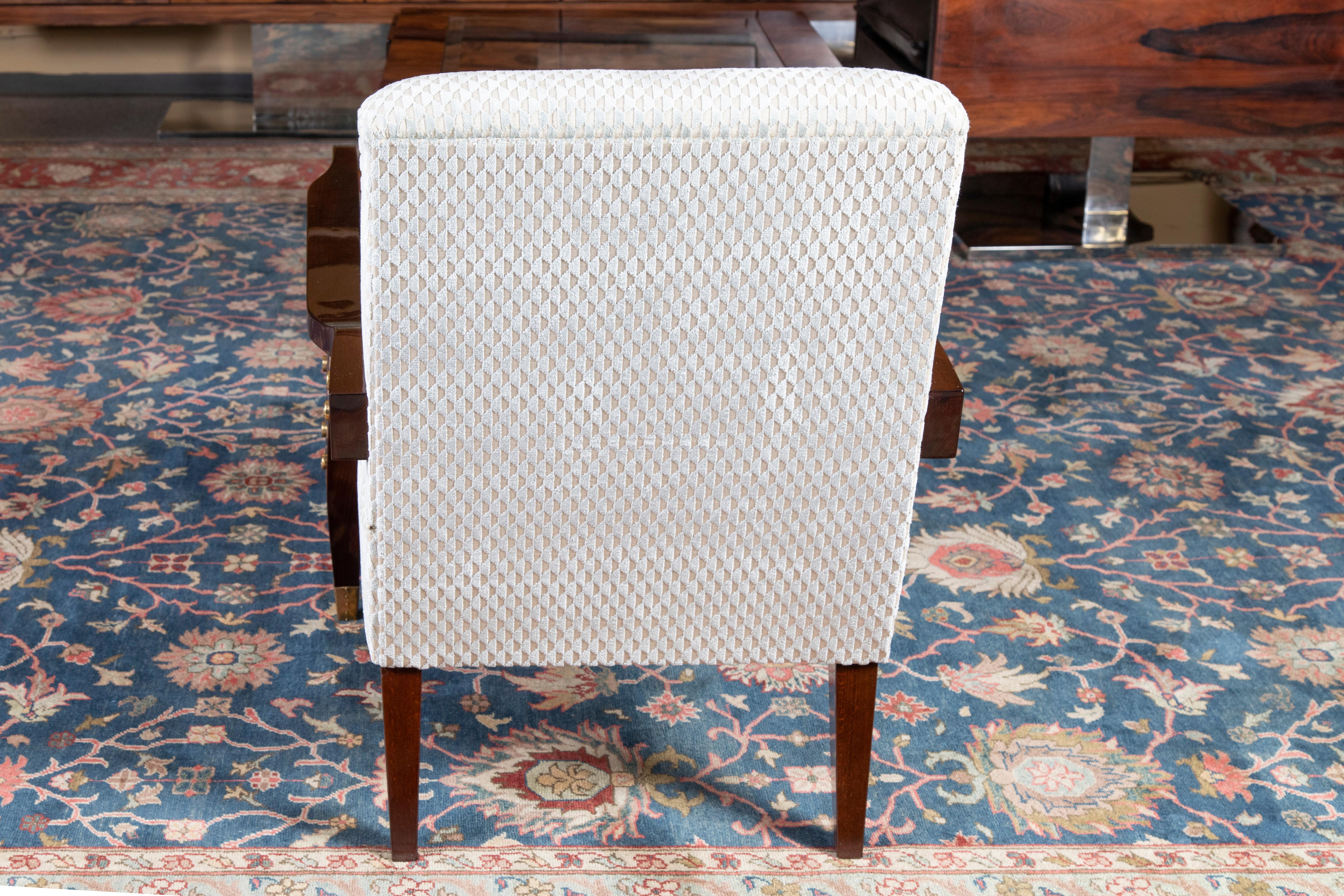 Chairs are newly re-upholstered in a light colored fabric. Their wooden arm supporters are gradually transferring into the 2 front legs, which have bras tips at the end. There are 6 brass decorative round elements on the outer side of each arm rest.