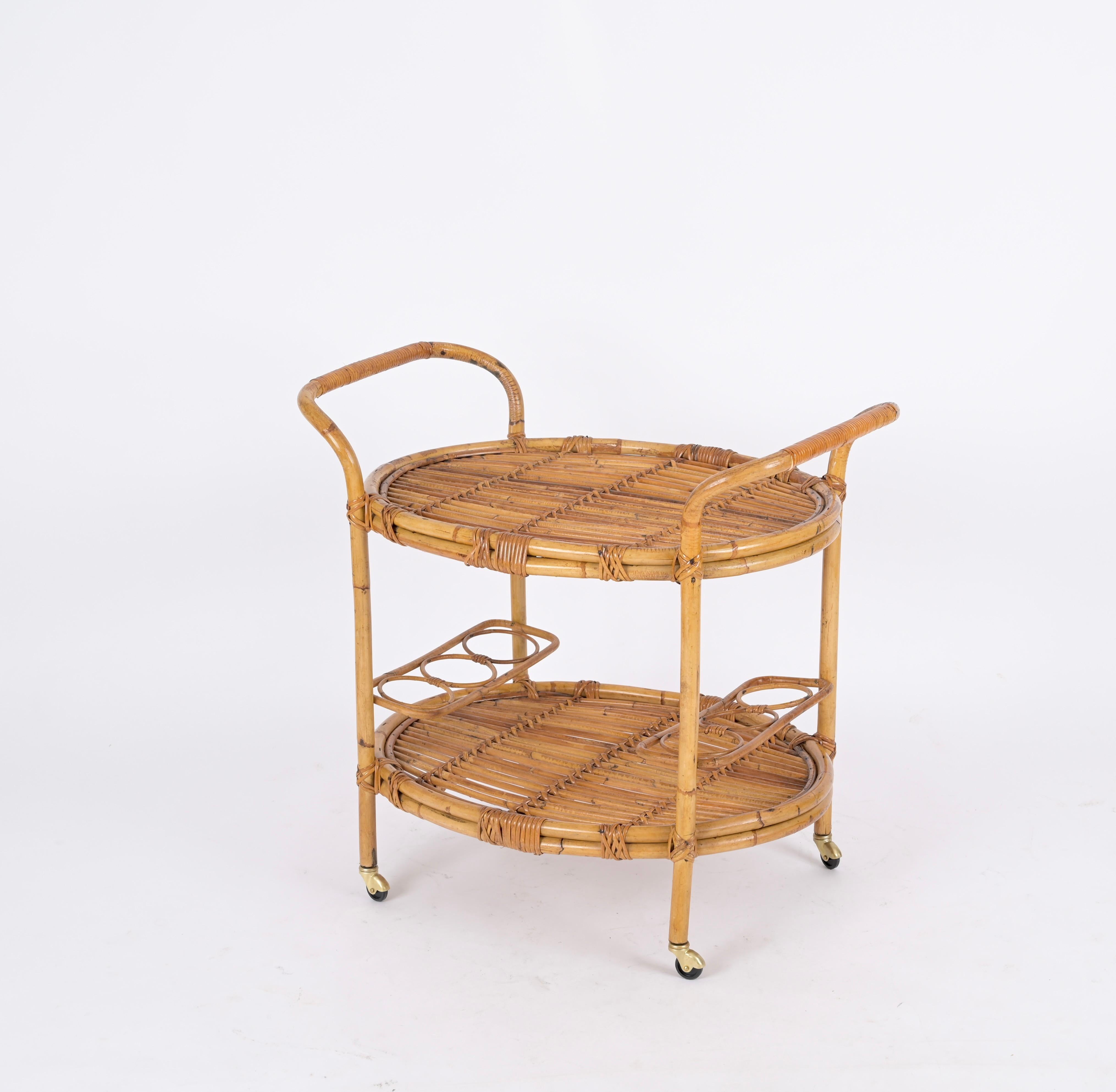 Marvellous mid-century oval bar cart trolley fully made in bamboo, curved rattan and wicker. This unique piece was hand-made with perfect proportions, great example of fine Italian craftsmanship from the 60s.

A wonderful piece with incredible