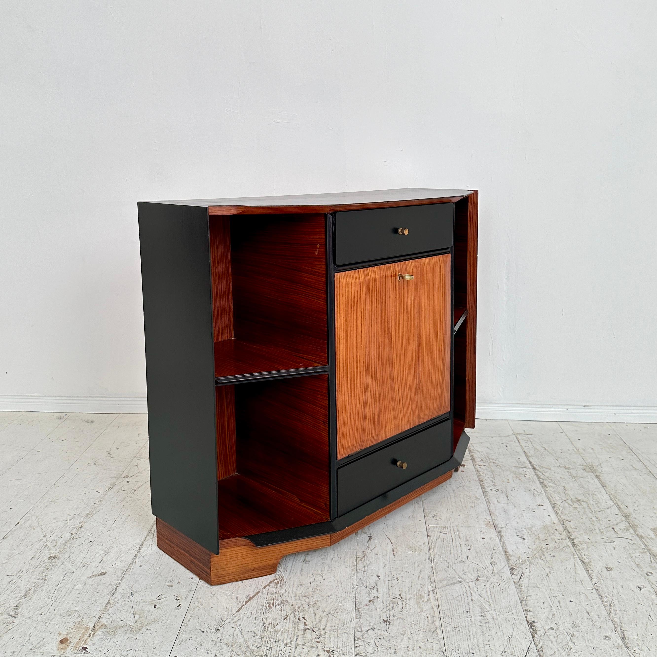 Experience the timeless elegance of mid-century Italian craftsmanship with this exquisite bar cabinet crafted around 1950. Meticulously fashioned from Zebrano wood and adorned with sleek black lacquer accents, it epitomizes sophistication and