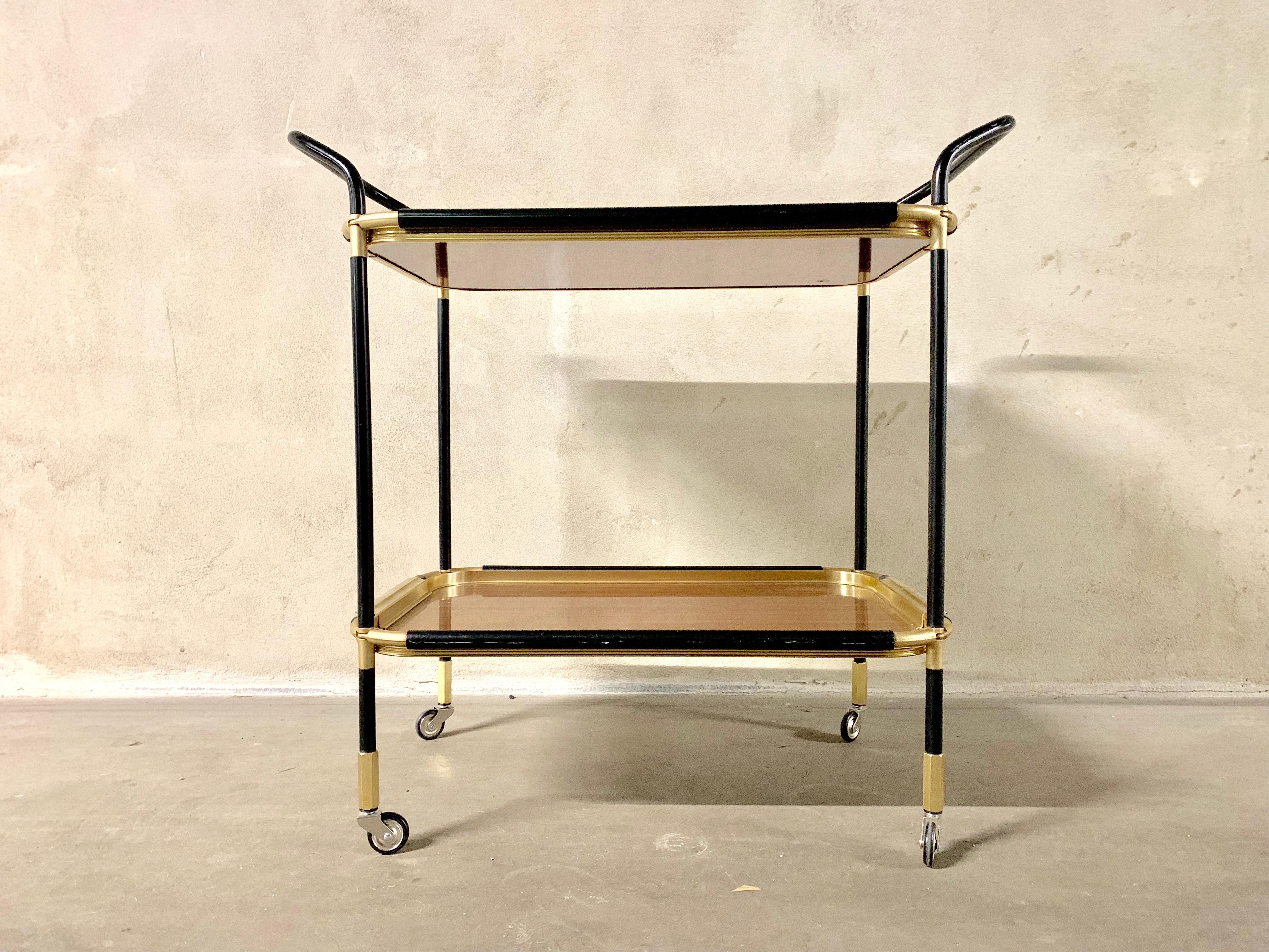 Beautiful bar cart or trolley in the style of Ico Parisi, the structure is in black painted metal tubular with golden metal details. Two removable trays are in wood and golden metal details.
The four wheels are in metal.
 