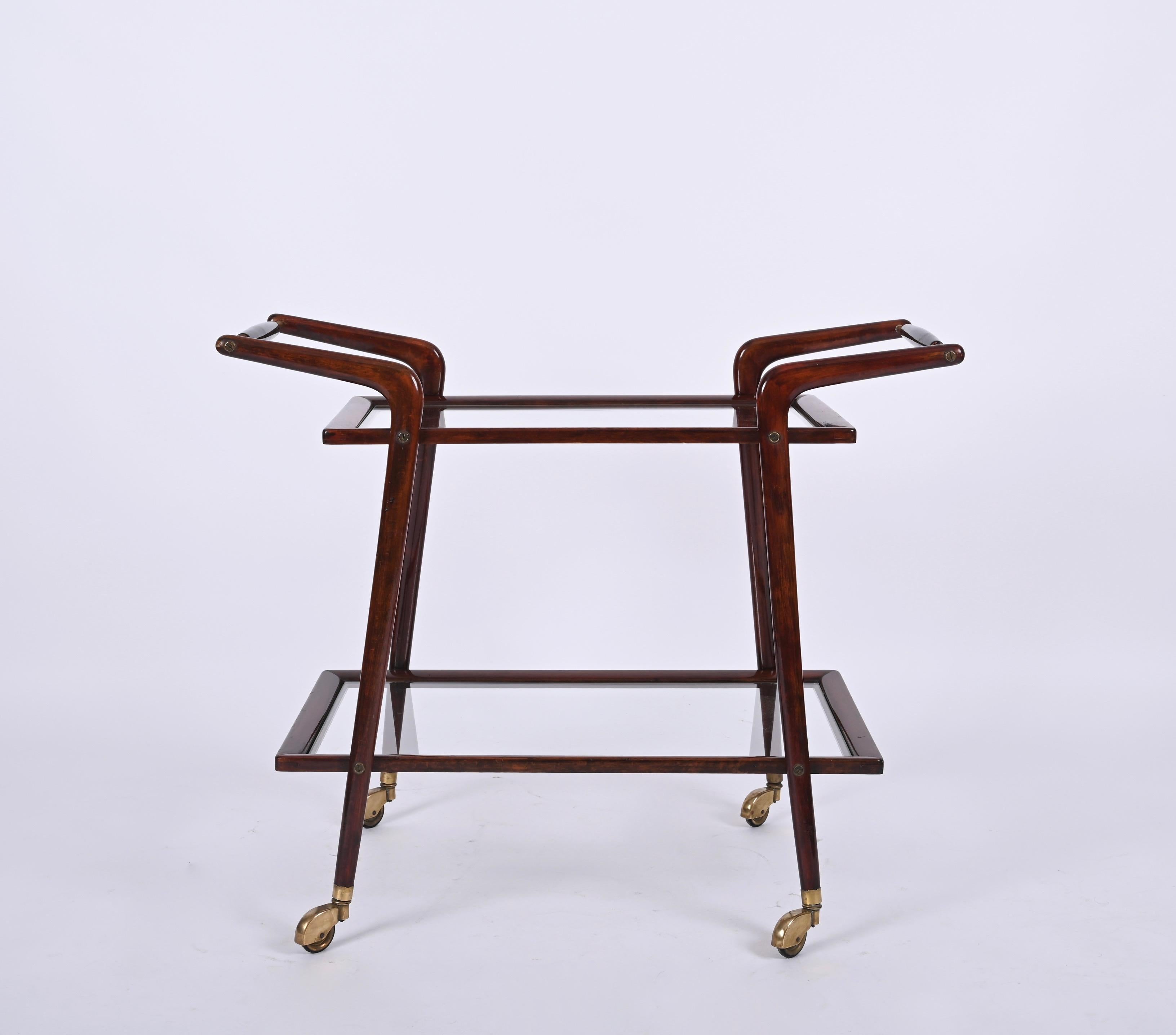 Marvellous Italian bar trolley designed by Cesare Lacca in the 1950s in Italy. 

The bar cart features a gorgeous symmetrical design with the two original crystal glass shelves, stunning curved legs and two handles in brass and black lacquered