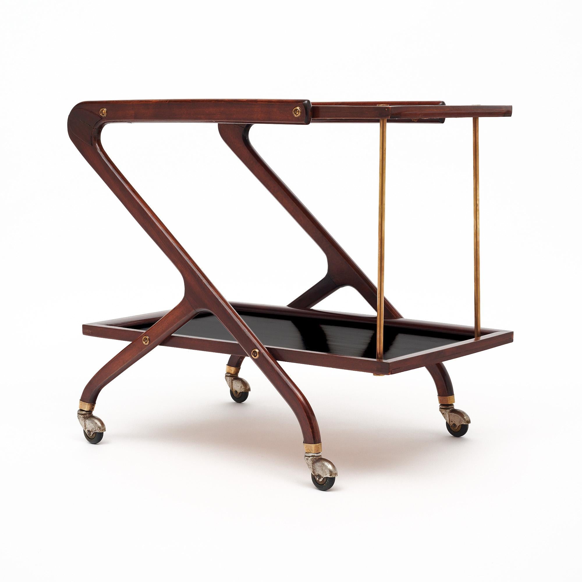 Chariot de bar de l'Italie du milieu du siècle, doté d'une structure en noyer massif et d'étagères en bois ébonisé. Les étagères sont également soutenues par des colonnes en laiton. La table est soutenue par des roulettes originales. Nous aimons les