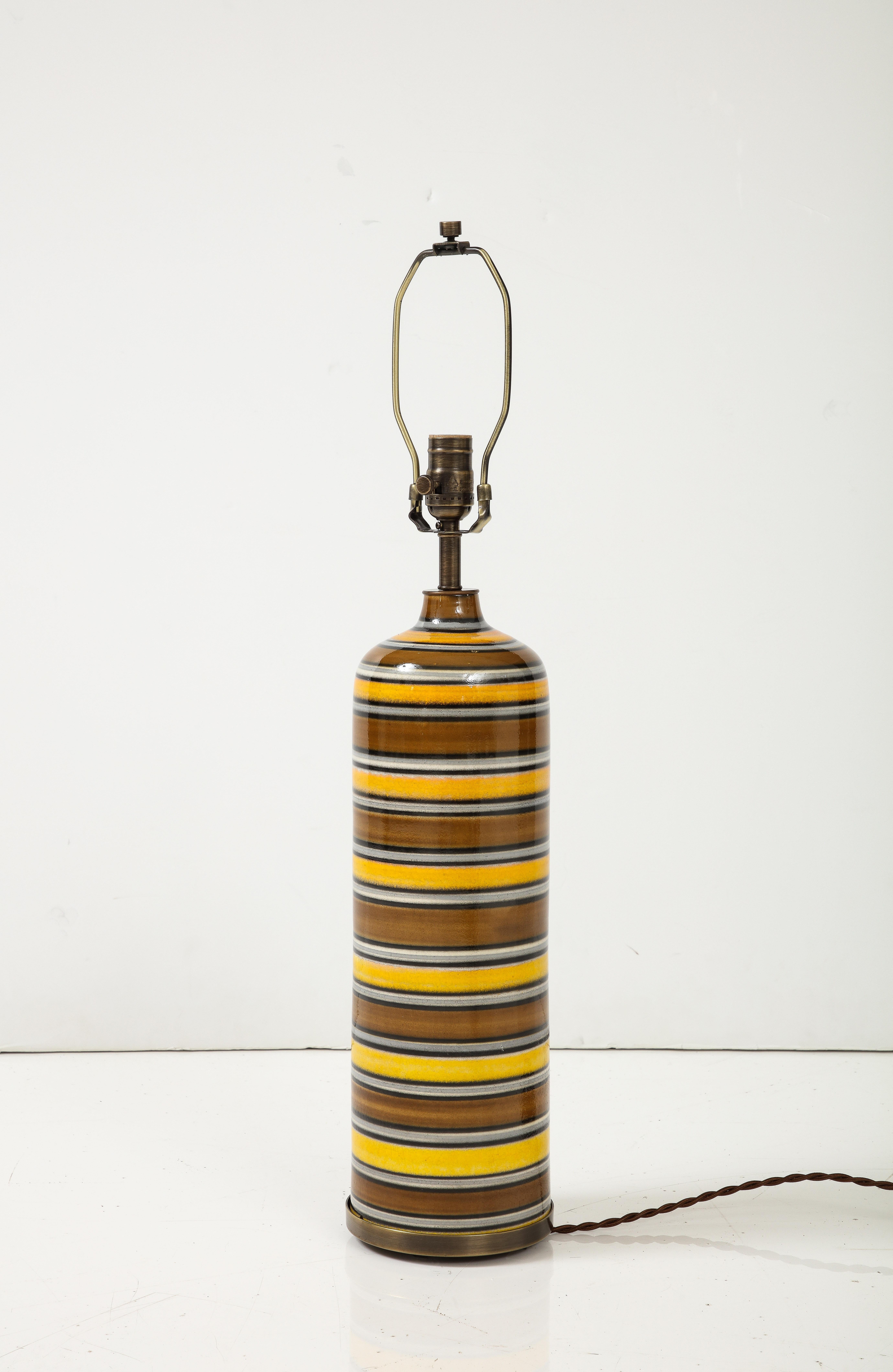 Italian midcentury ceramic lamp featuring a striped column body in brown, yellow and white glaze. Rewired for use in the USA. Uses 1 Edison type bulb, 100 watt max. Ceramic base signed on bottom. Lamp is set into an aged bronze base.