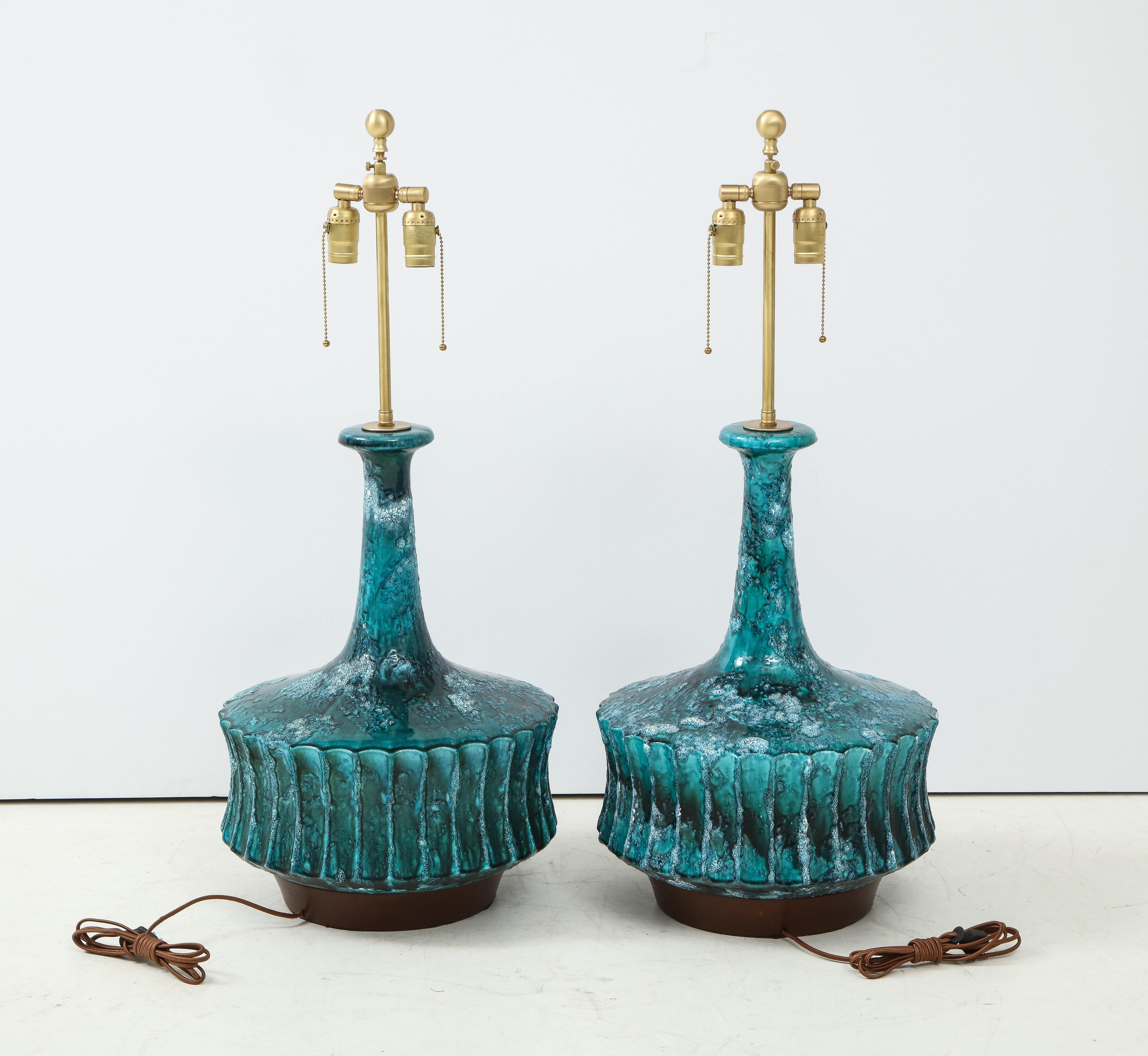 Pair of heavily glazed ceramic lamps with fluted body and elongated neck sitting on stacked walnut bases. Rewired for use in the USA with double pull chain sockets.