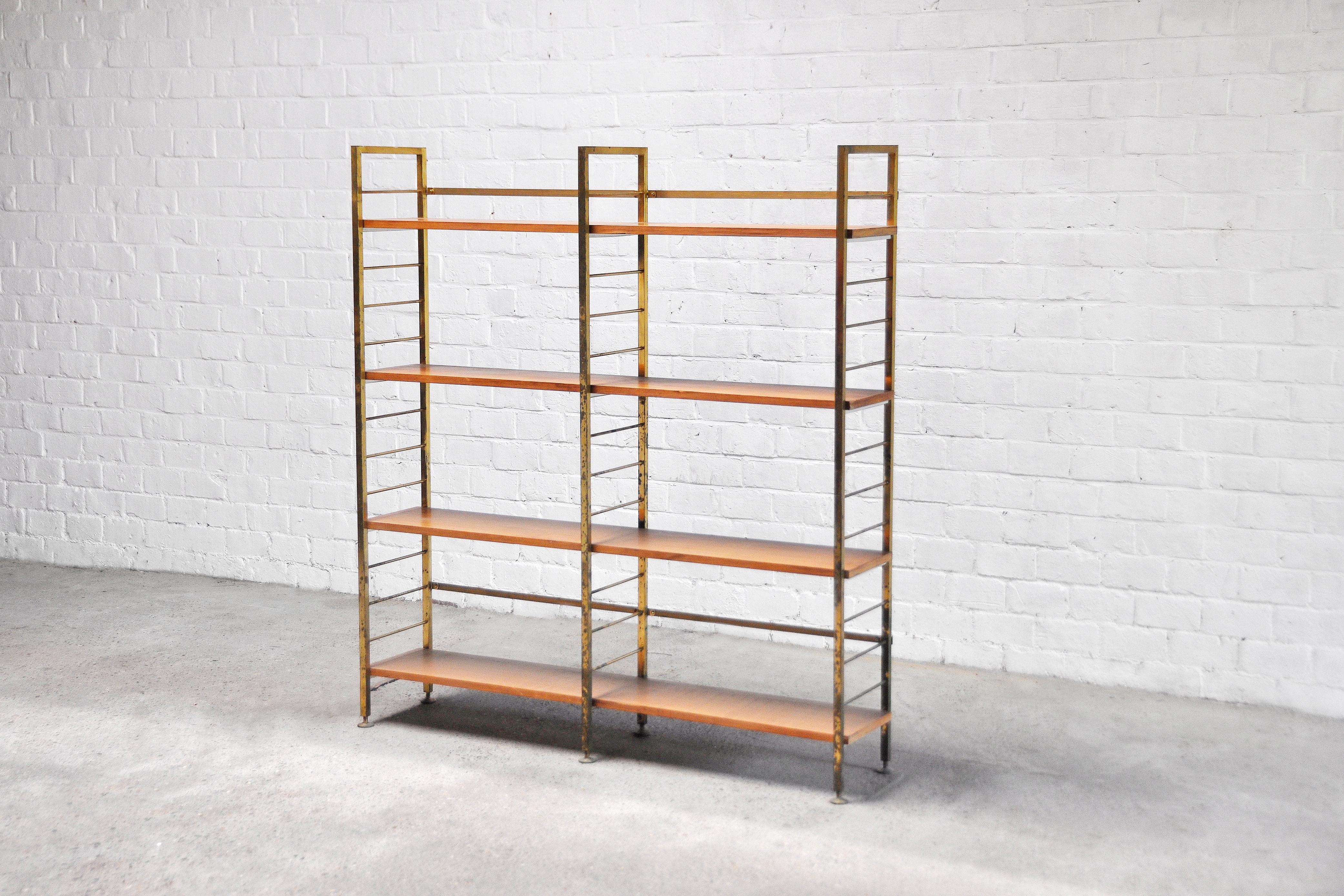 A unique 1960’s bookcase or shelving unit. Italian designer manufacturing, consisting out of a brass structure with wooden shelves. Wear consistent with age and use. Heavily patinated brass left intentionally in original condition. 