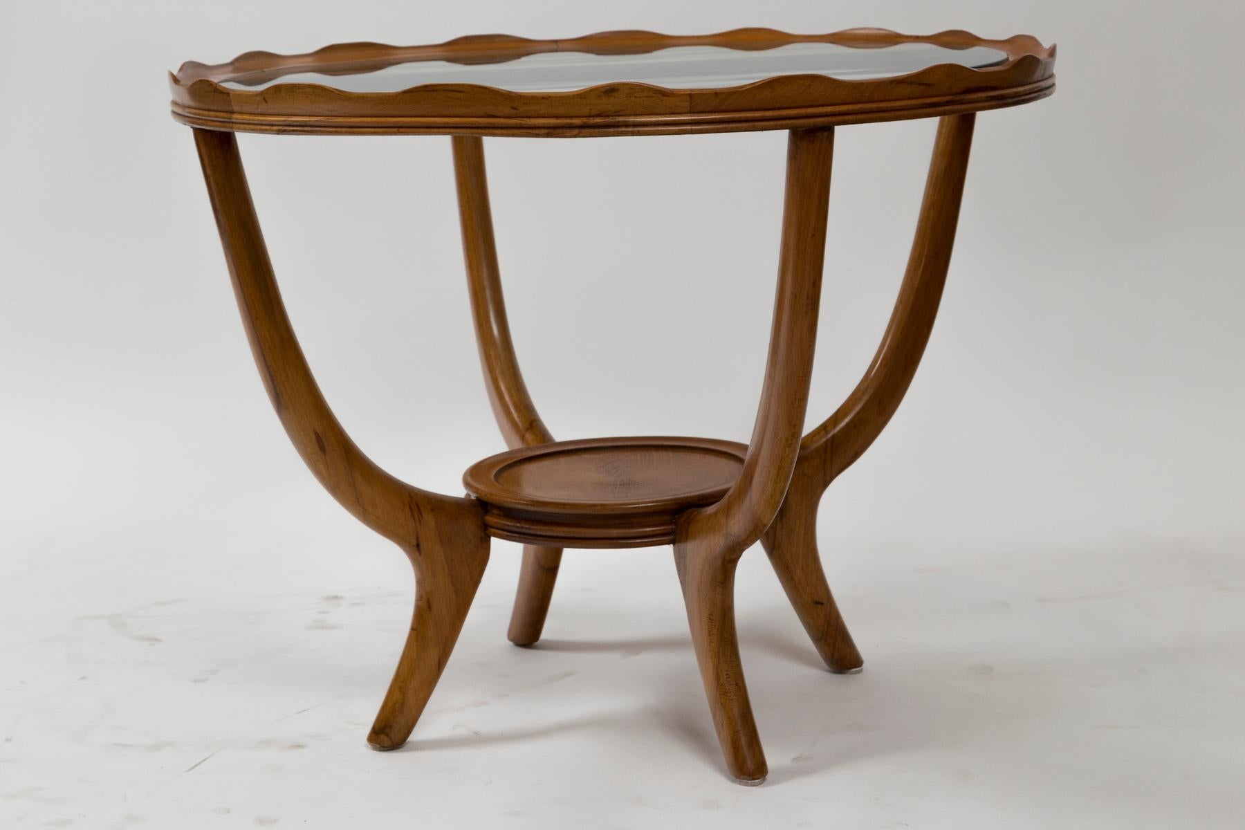 Charming circular two tier low table in solid light fruitwood composed of a scalopped gallery with inset glass plateau upheld by four elegant curving legs

Origin: Italy

Condition: Very good, glass is shown with a few minor surface