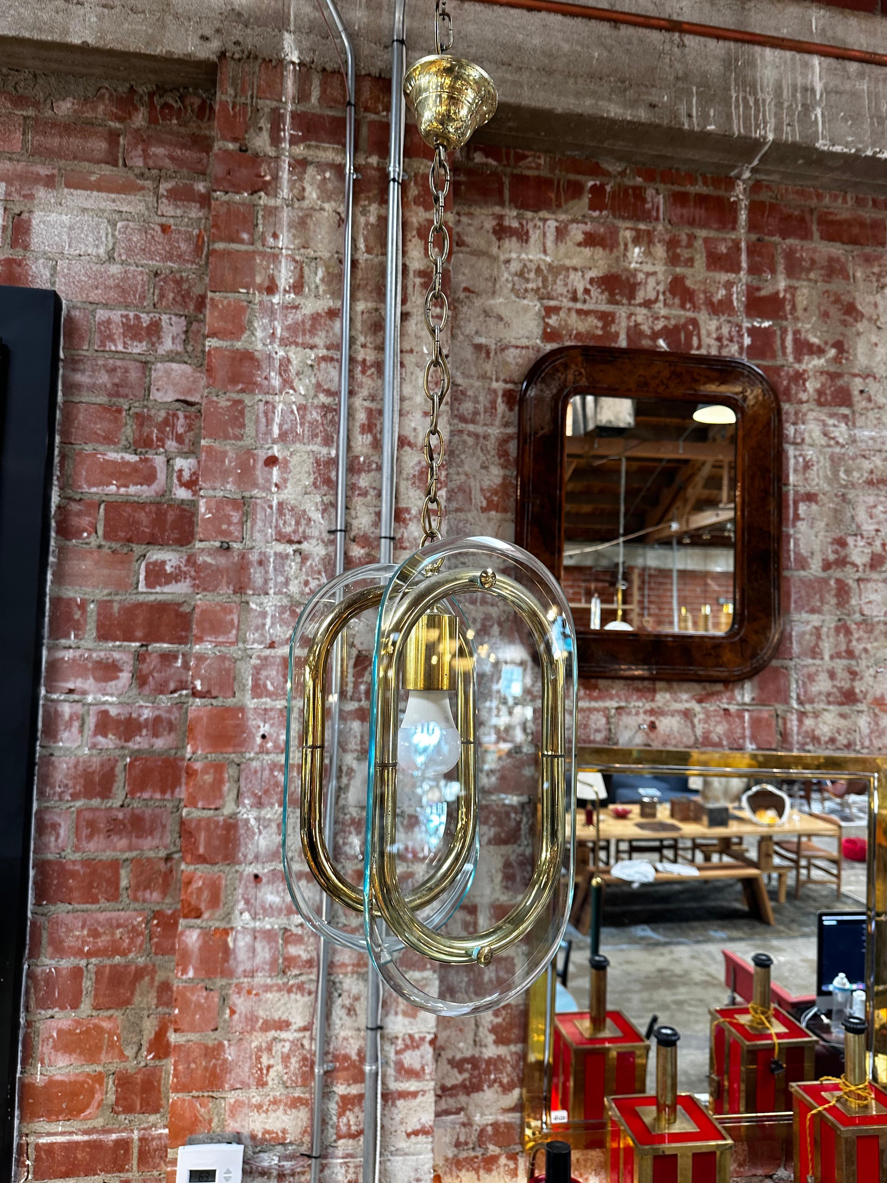 The Mid Century Italian Brass and Glass Pendant from the 1970s is a vintage lighting fixture characterized by its sleek design, featuring brass elements and glass components. This pendant exudes the distinctive style of mid-century Italian