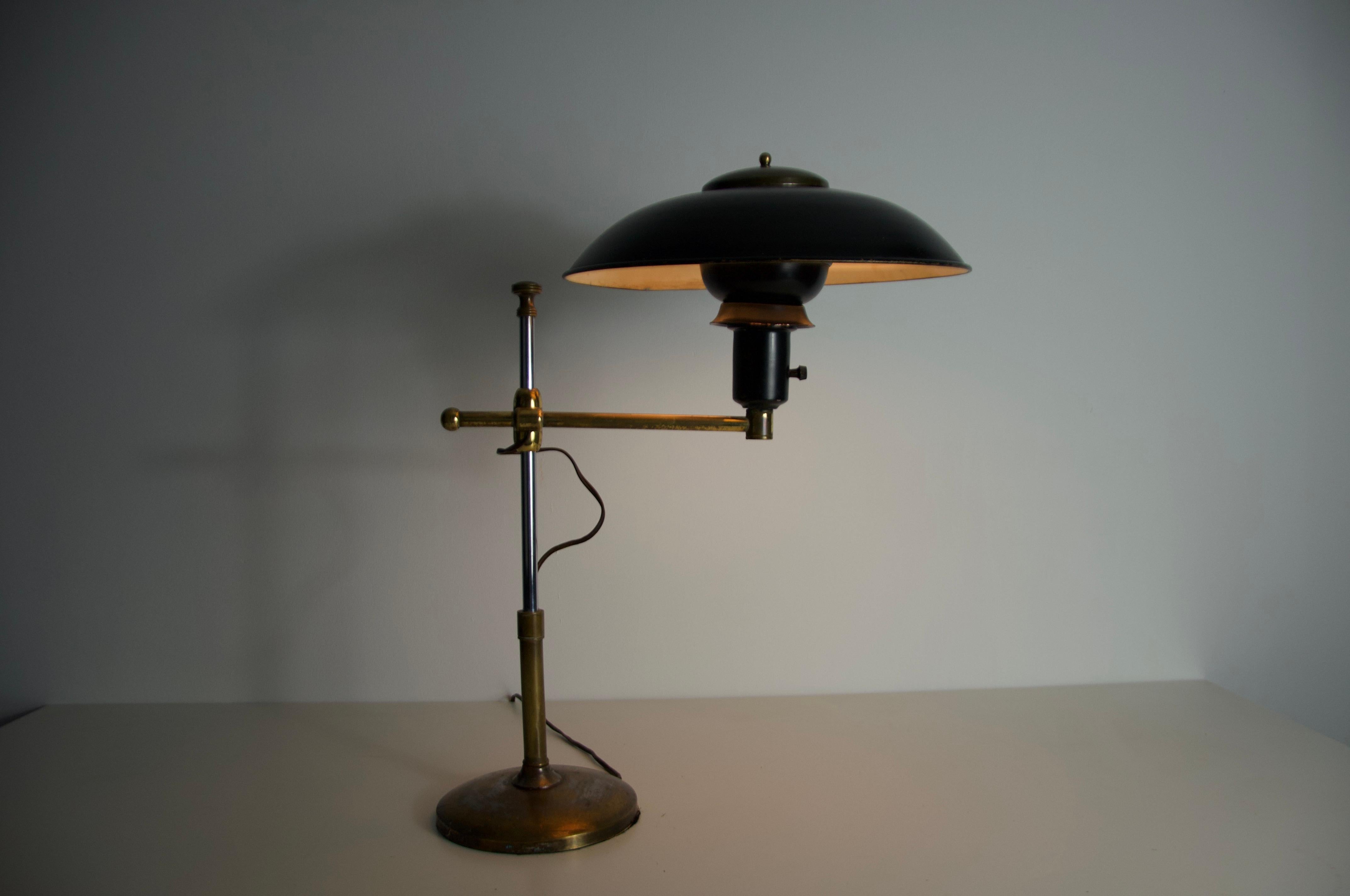 This striking mid-century table lamp from Italy, dating to the 1960s, features a beautifully balanced combination of brass and lacquered metal. The design is both functional and sculptural, with an adjustable arm and height mechanism that allows for