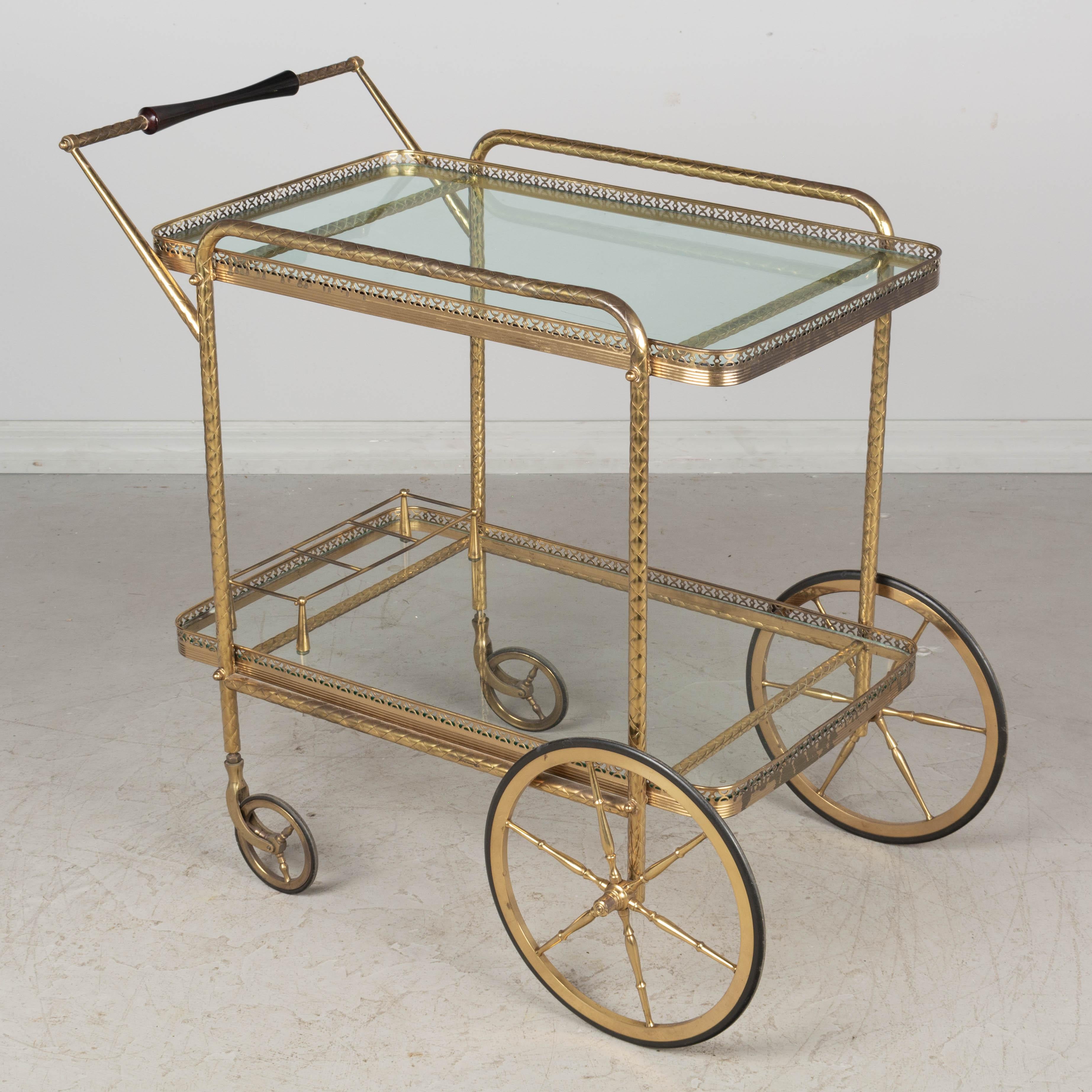 A Mid-Century modern Italian brass bar cart with mahogany handle and glass shelves with bottle rack. Nice patina, as found, but may be polished to a high shine if desired. Rolls smoothly.
Contact us for a competitive shipping quotation. Please