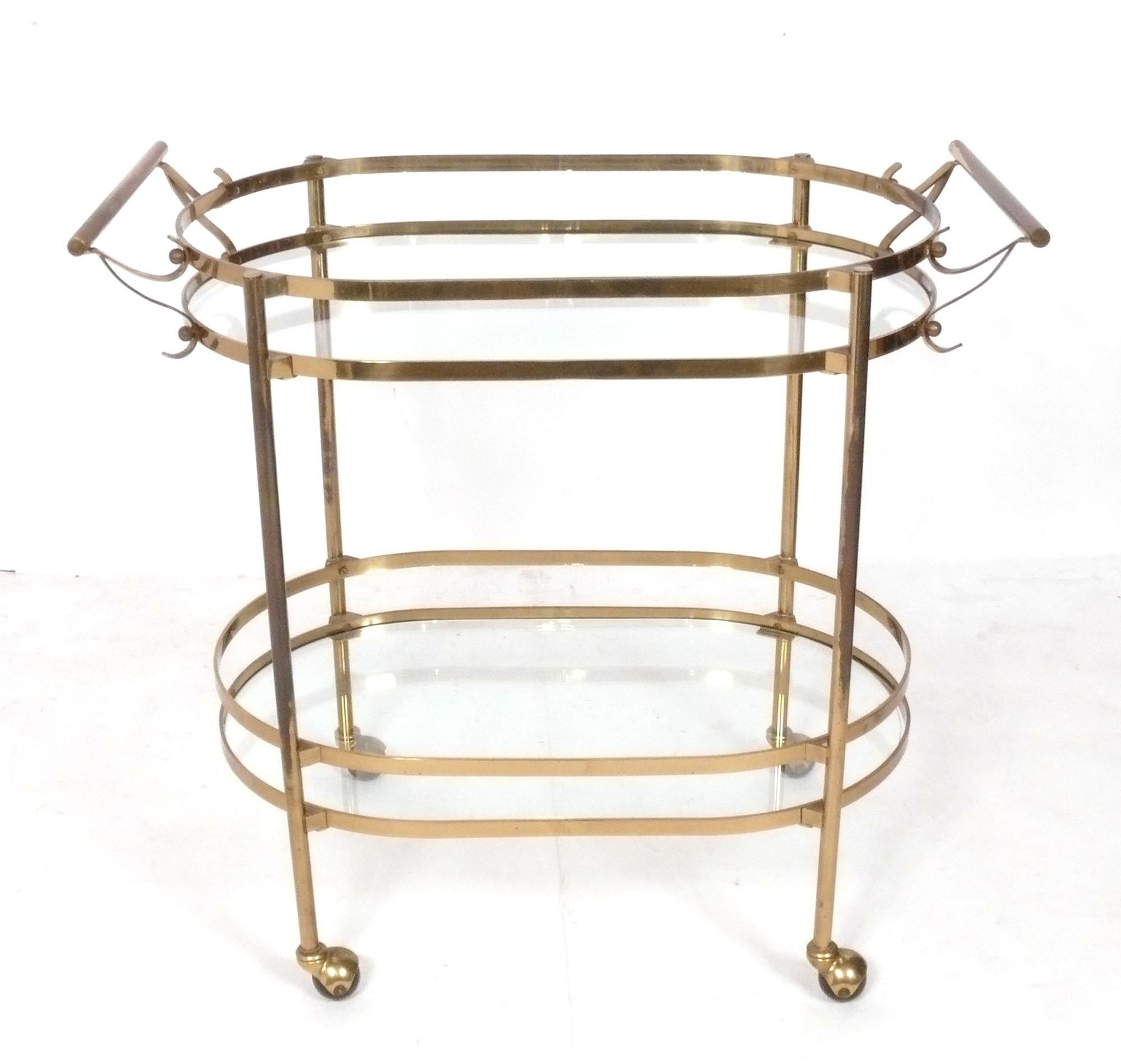 Chariot de bar en laiton du milieu du siècle, probablement italien, vers les années 1960. Deux grandes étagères ovales en verre offrent de nombreuses possibilités de rangement. Peut être utilisé comme chariot de bar, chariot de service ou comme