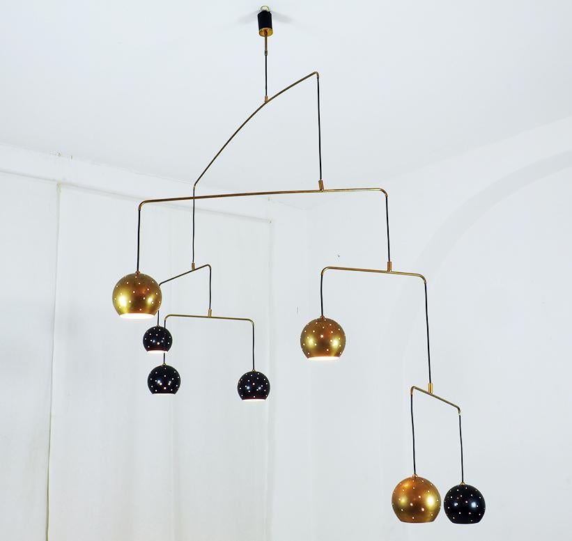 Original Italian brass mobile chandelier manufactured in a very small handcraft production in Milano, 20th century
Large, magic and poetical mobile chandelier with brass and black suspending spheres, it can moves with the flow of air.
Wholly in